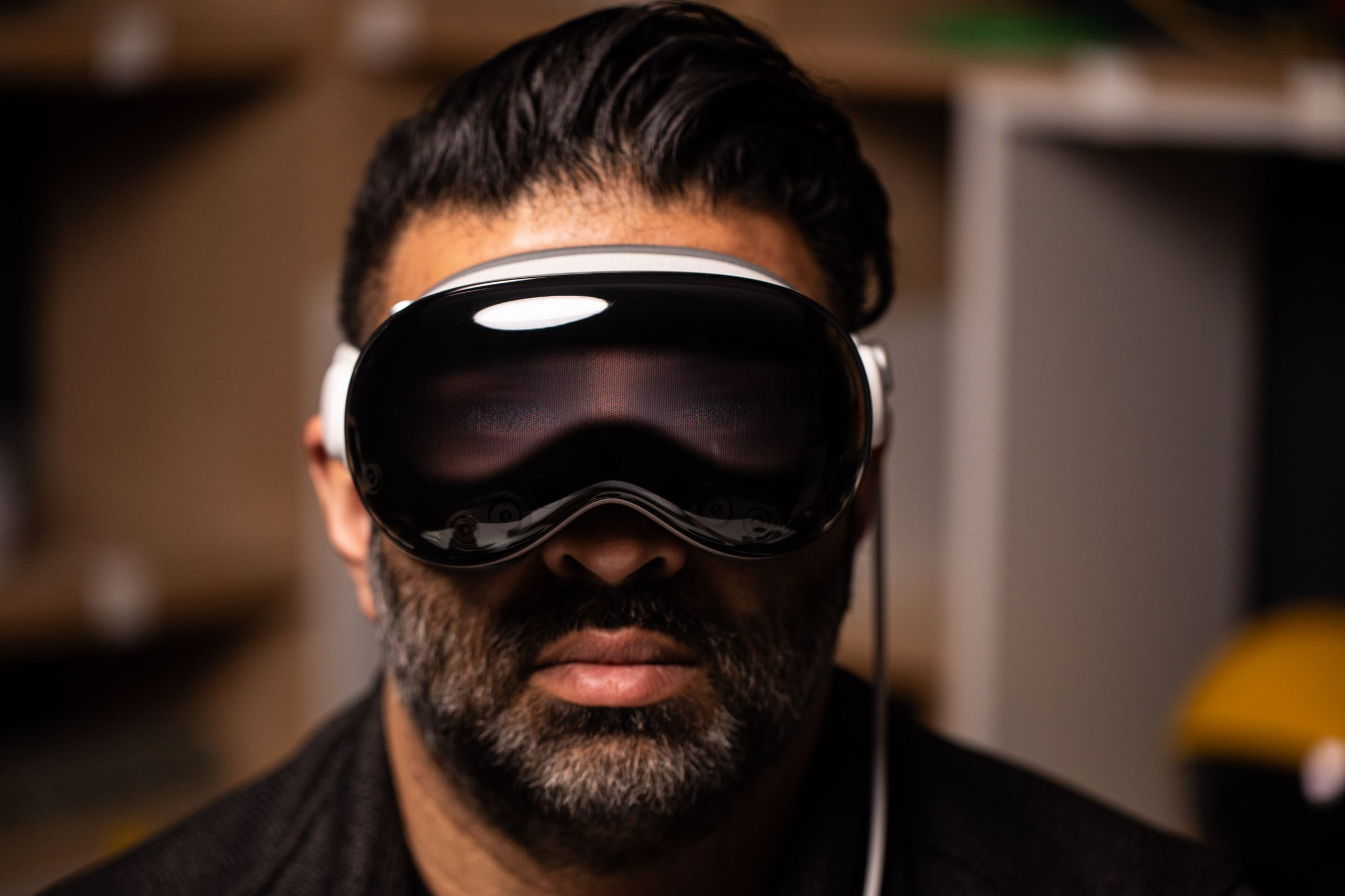 Nilay Patel wears the Vision Pro, with the front display showing a faint image of his eyes.