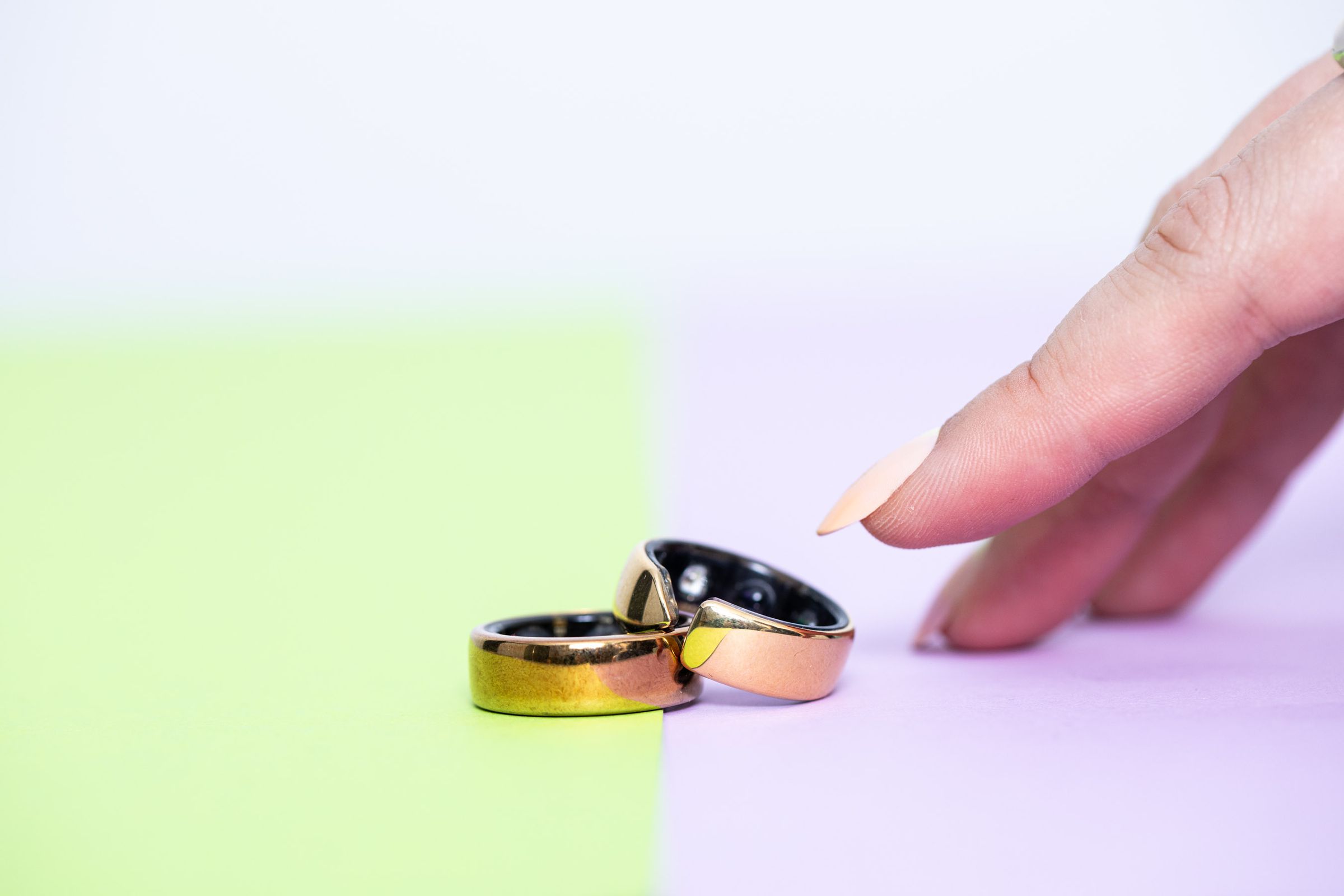 The Evie Ring on top of the Oura Ring while a hand reaches out toward them