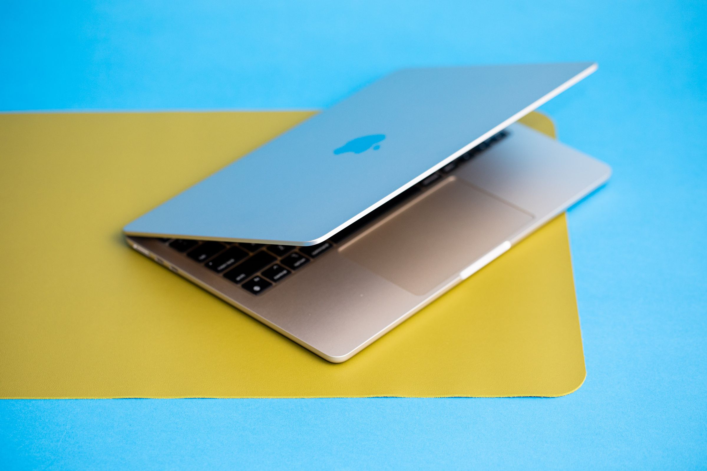 The 13-inch MacBook Air partially open sitting on a yellow mat.