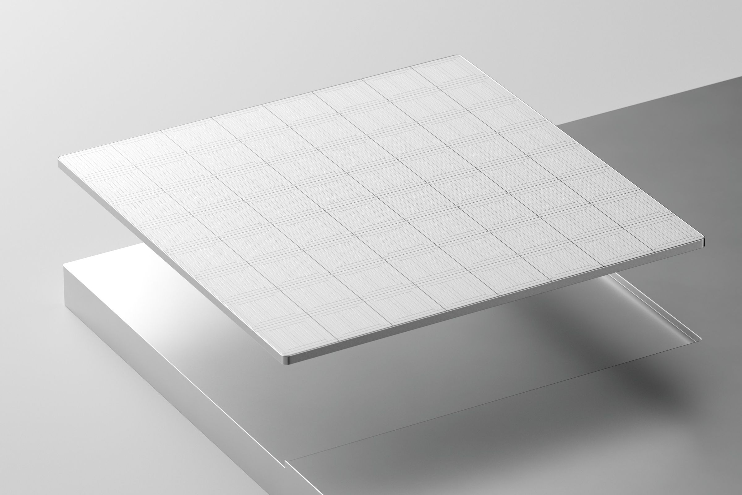 A white tile representative of a computer chip above a shiny silver metal surface that the chip appears to have been milled out of