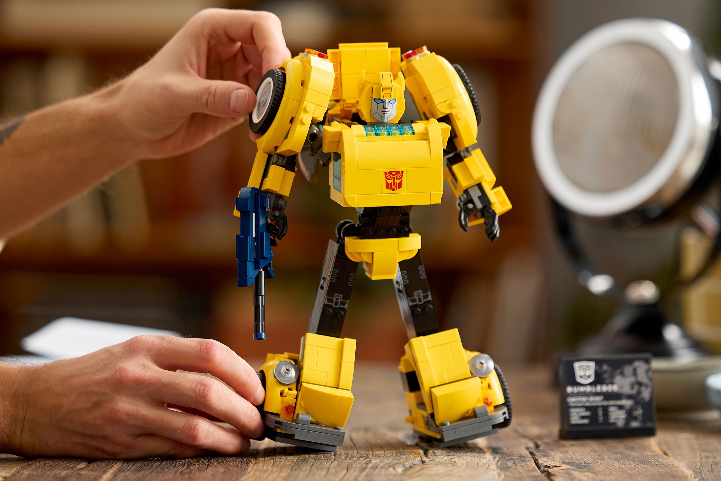 A person poses the Lego Transformers Bumblebee set in robot mode on a table.