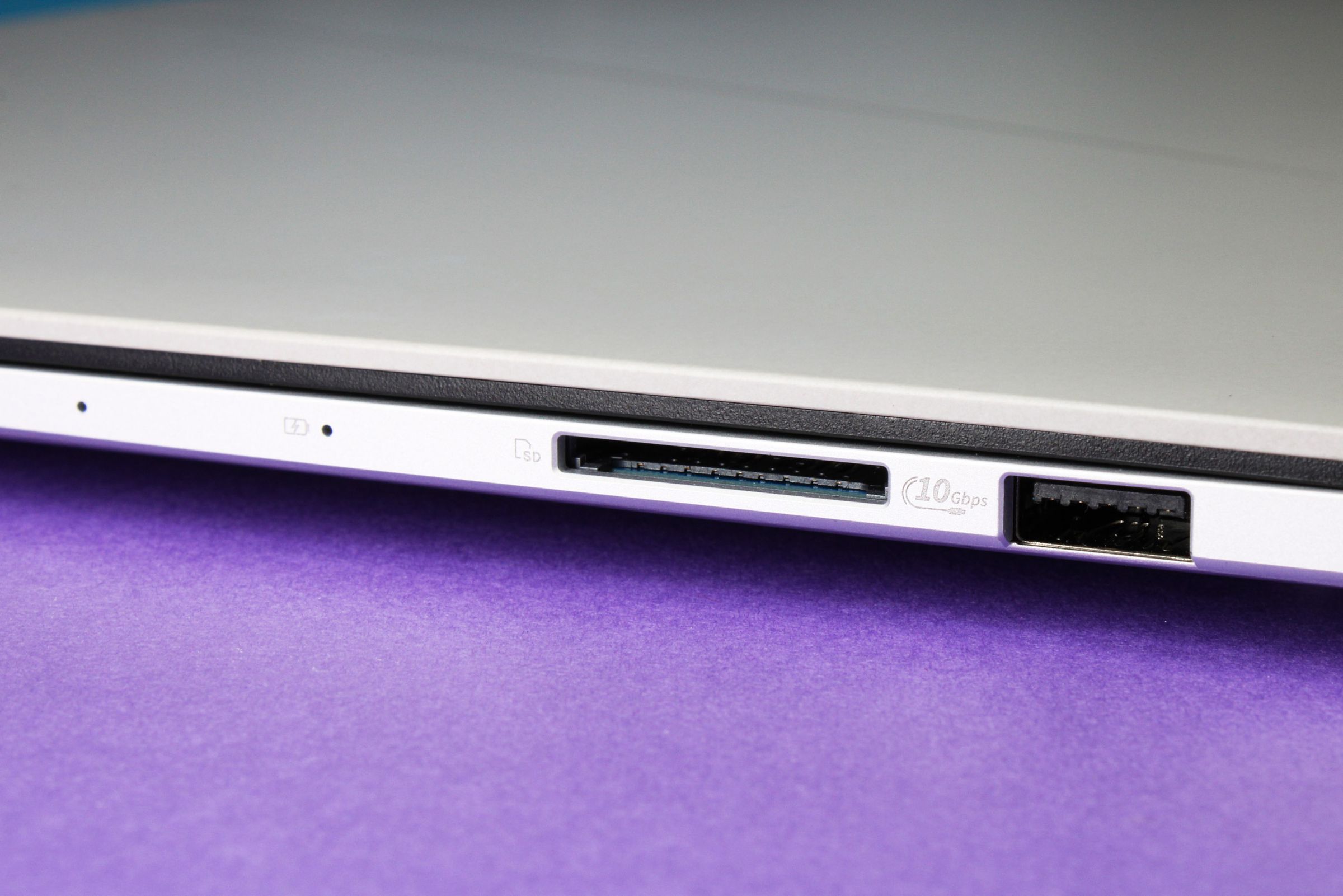 A close up of a laptop’s ports on top of a purple surface.