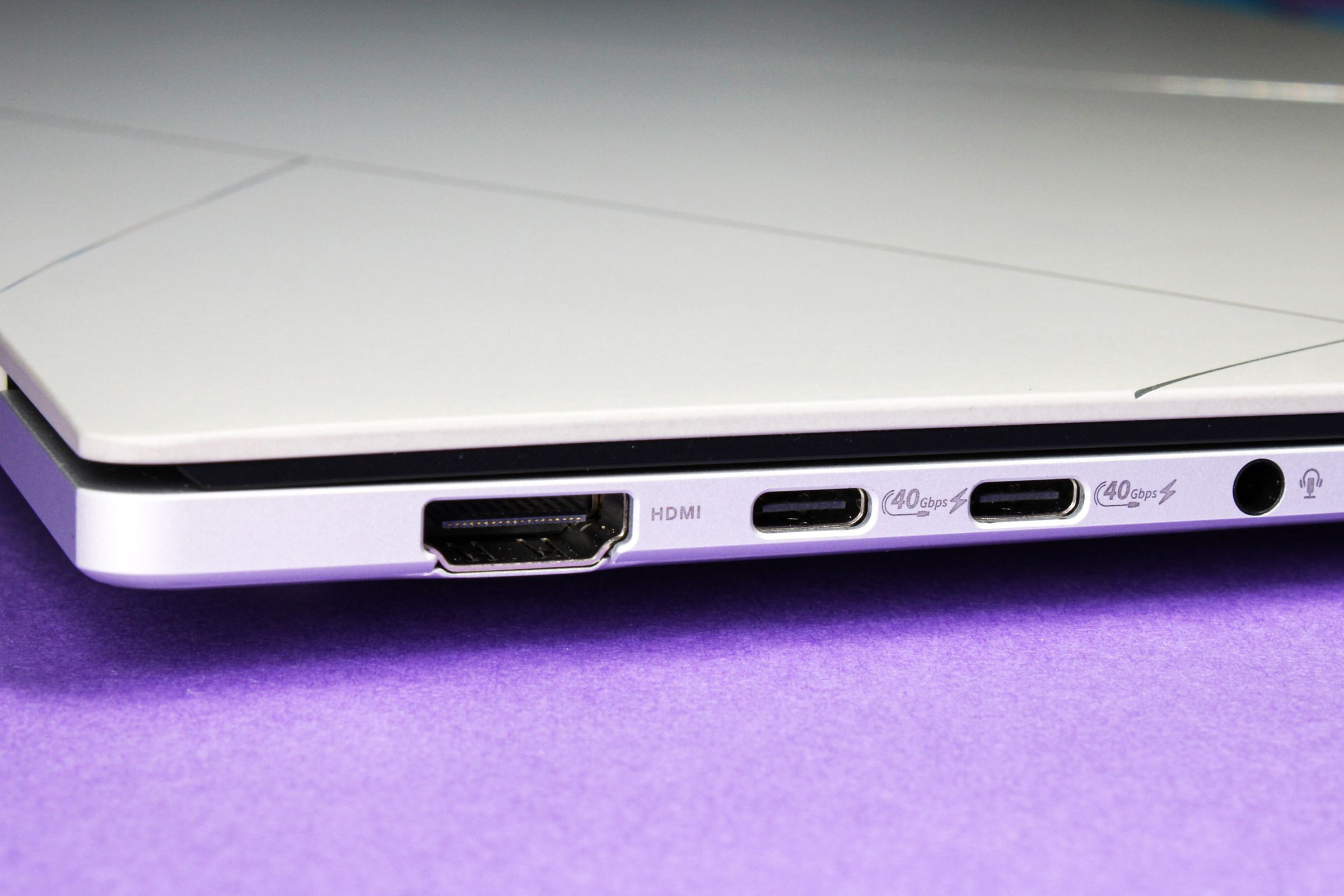 A close up of a laptop’s ports on top of a purple surface.