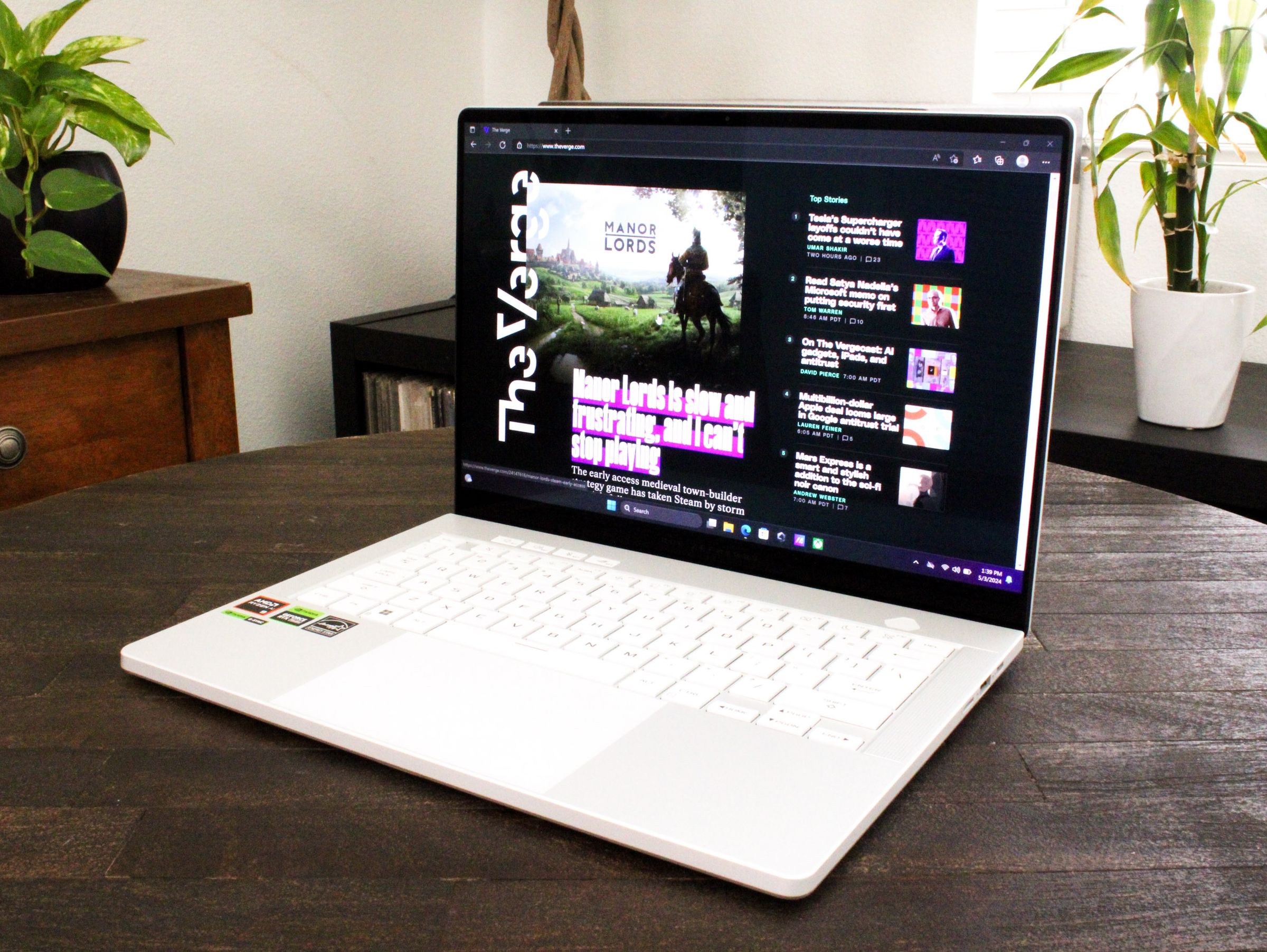 An open and powered on laptop sitting on top of a dark wood table.