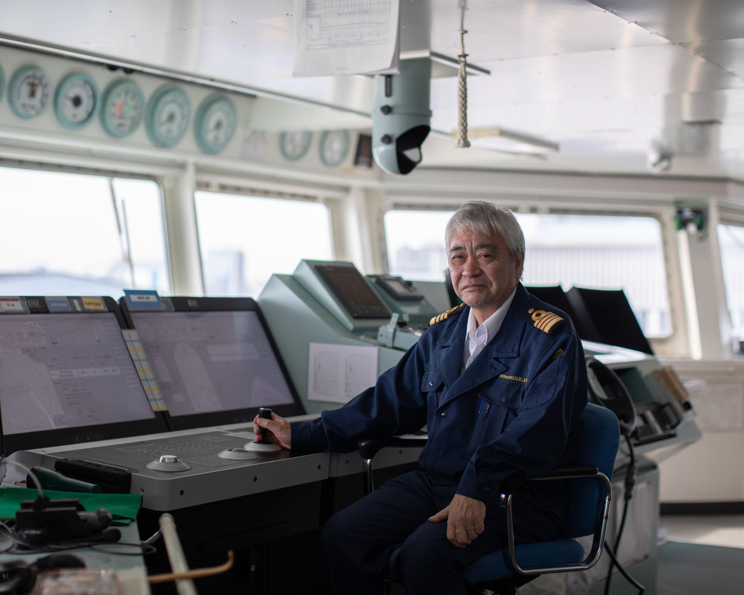 Captain Shoichi Suzuki sits in front of the control panels in the bridge of the Ocean Link.