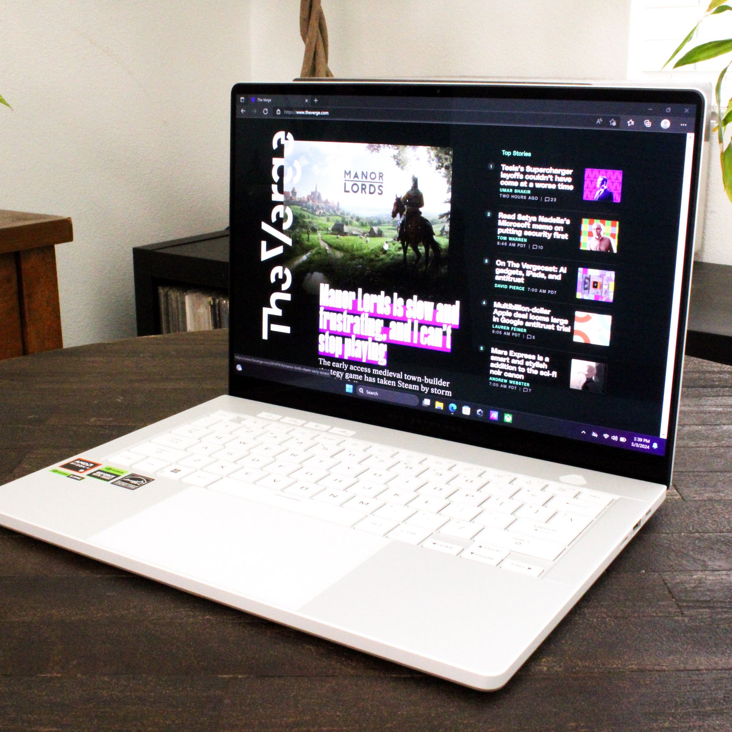 An open and powered on laptop sitting on top of a dark wood table.