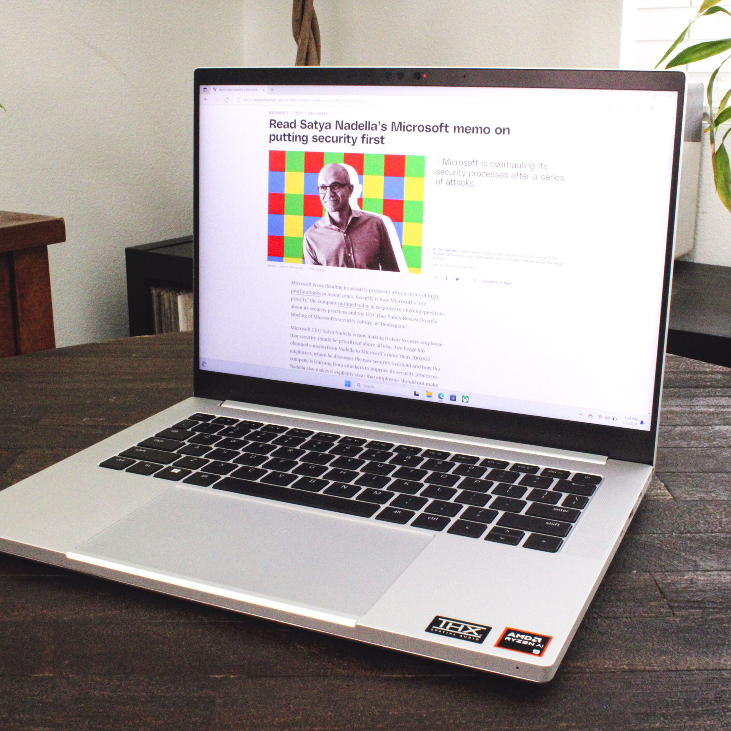 An open and powered on laptop sitting on top of a dark brown wood table.