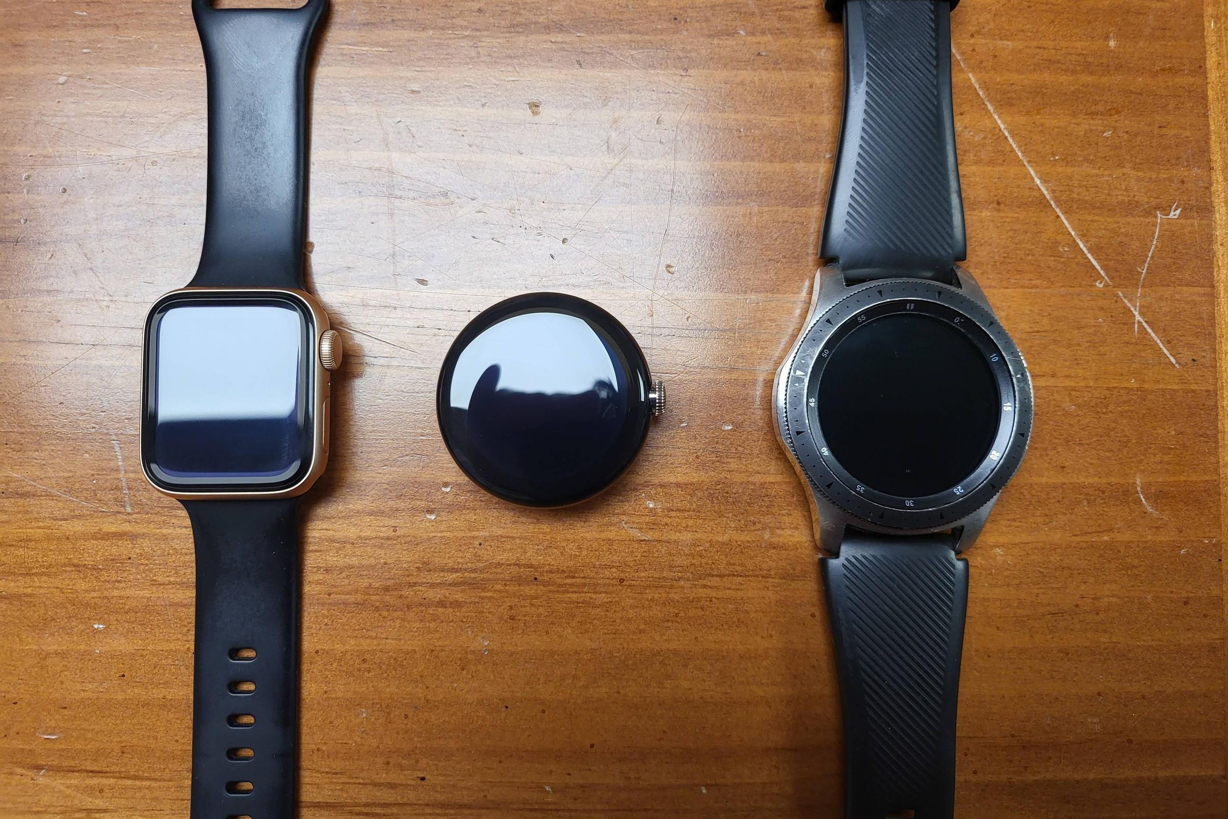 Pixel Watch between a 40mm Apple Watch (left) and 46mm Samsung Galaxy Watch.