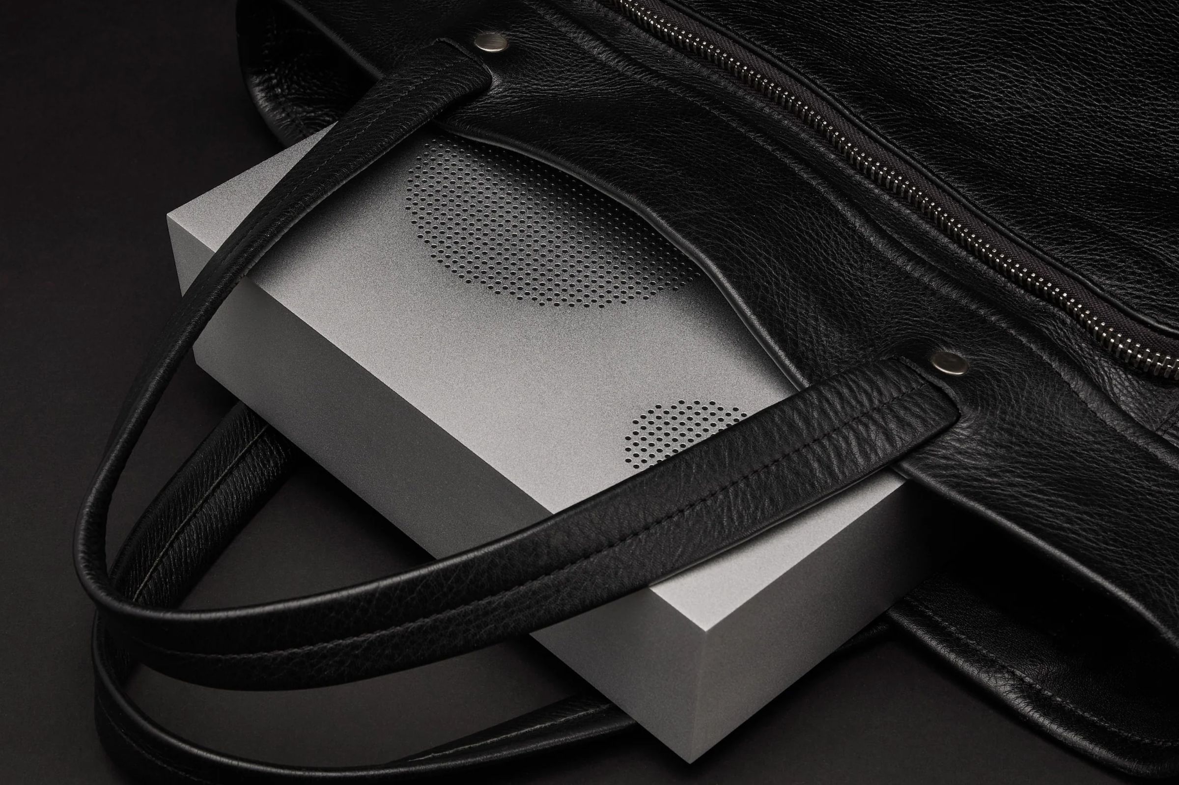 The all-metal Nocs Labs Monolith x Aluminum speaker in a silver finish half inserted into a bag.