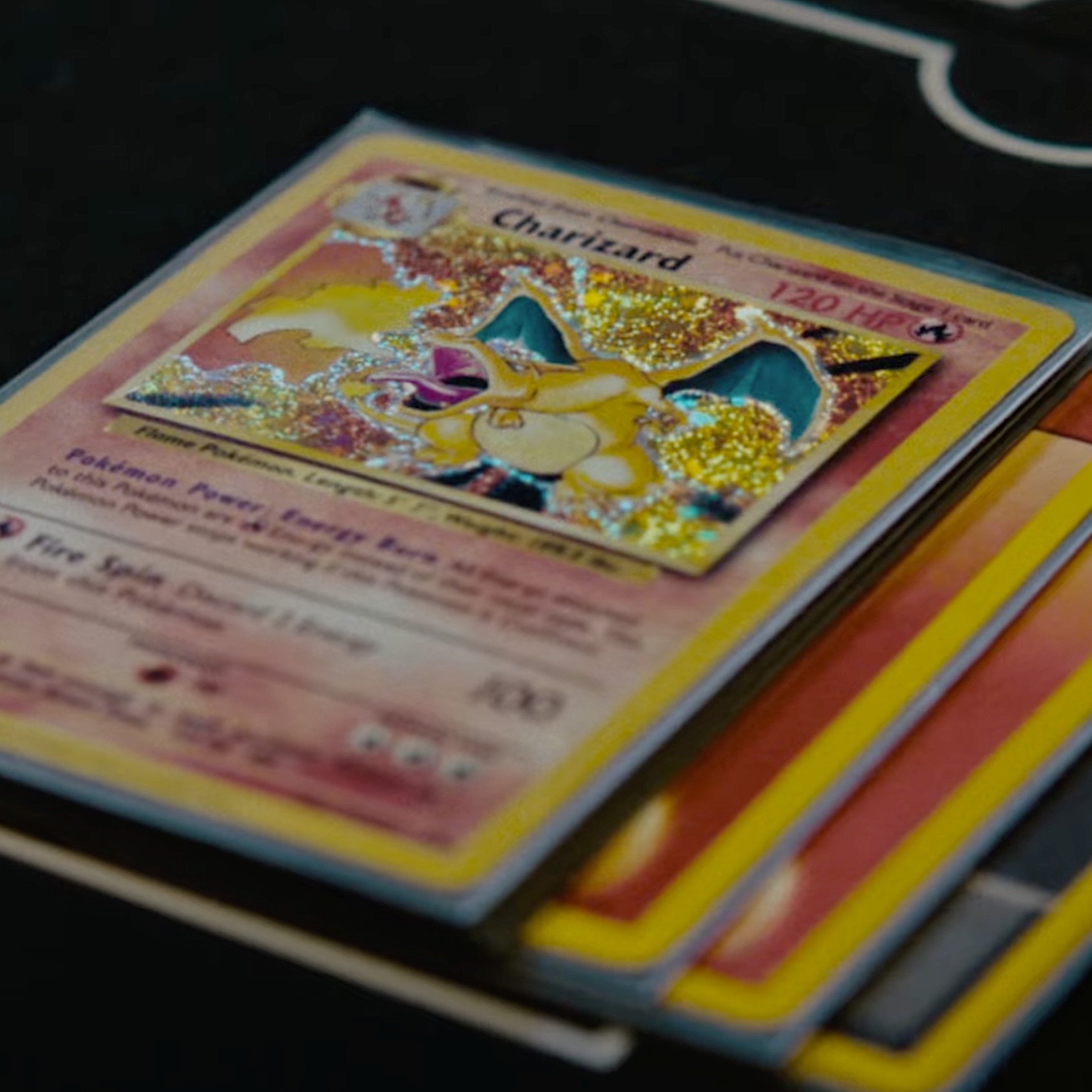 A closeup of a Charizard card and three energy cards stacked beneath it.