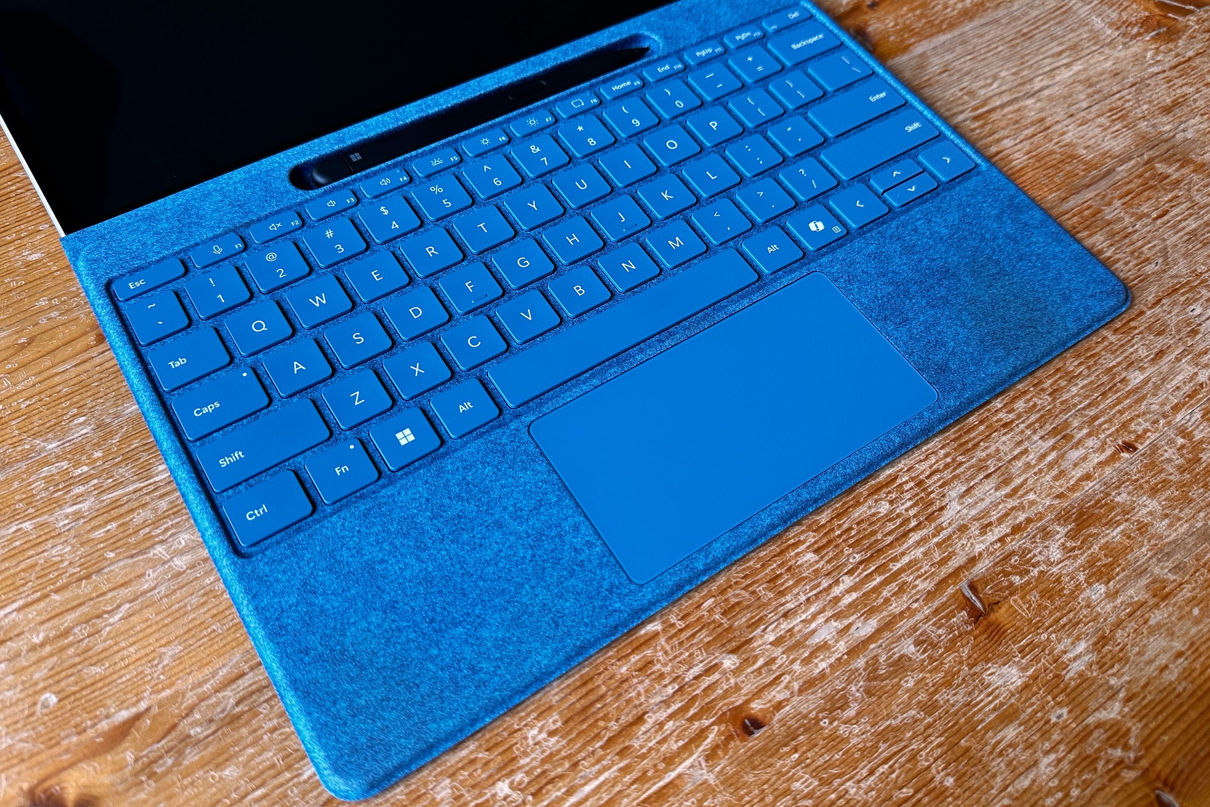 Close-up of a blue keyboard with fabric on the palm rests. It shows some dark yellowish staining, as if from sweat, where the palms rest in use