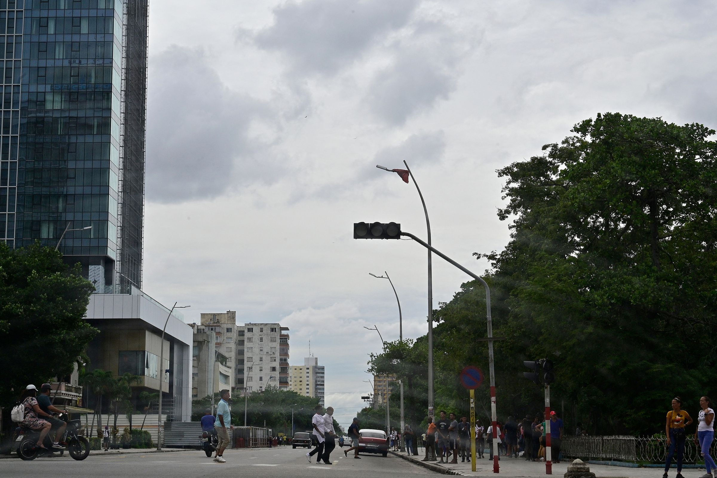 People cross a street while a traffic light is off.