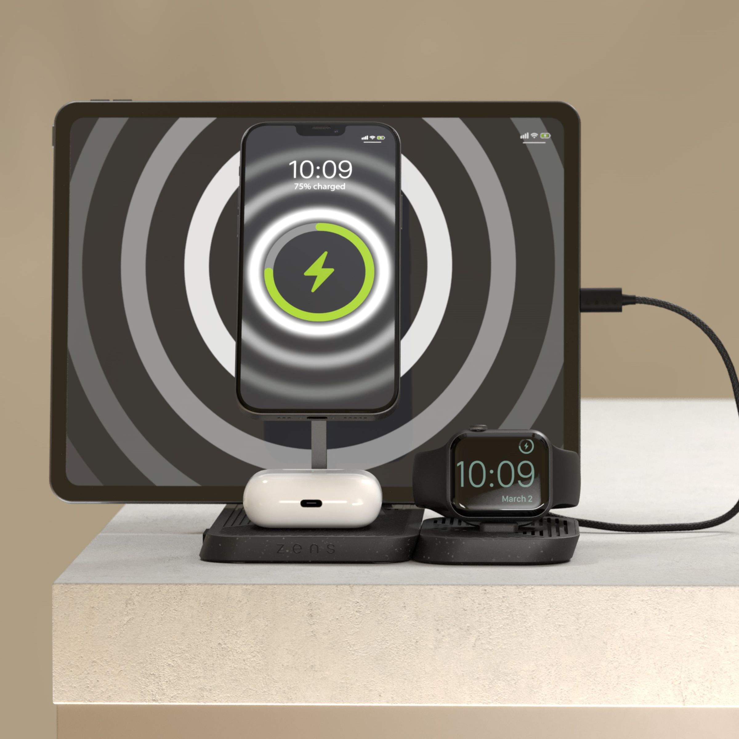 The Zens 4-in-1 multicharger on a table, wirelessly charging a MagSafe iPhone, Apple Watch, AirPods case, and wired USB-C iPad simultaneously.