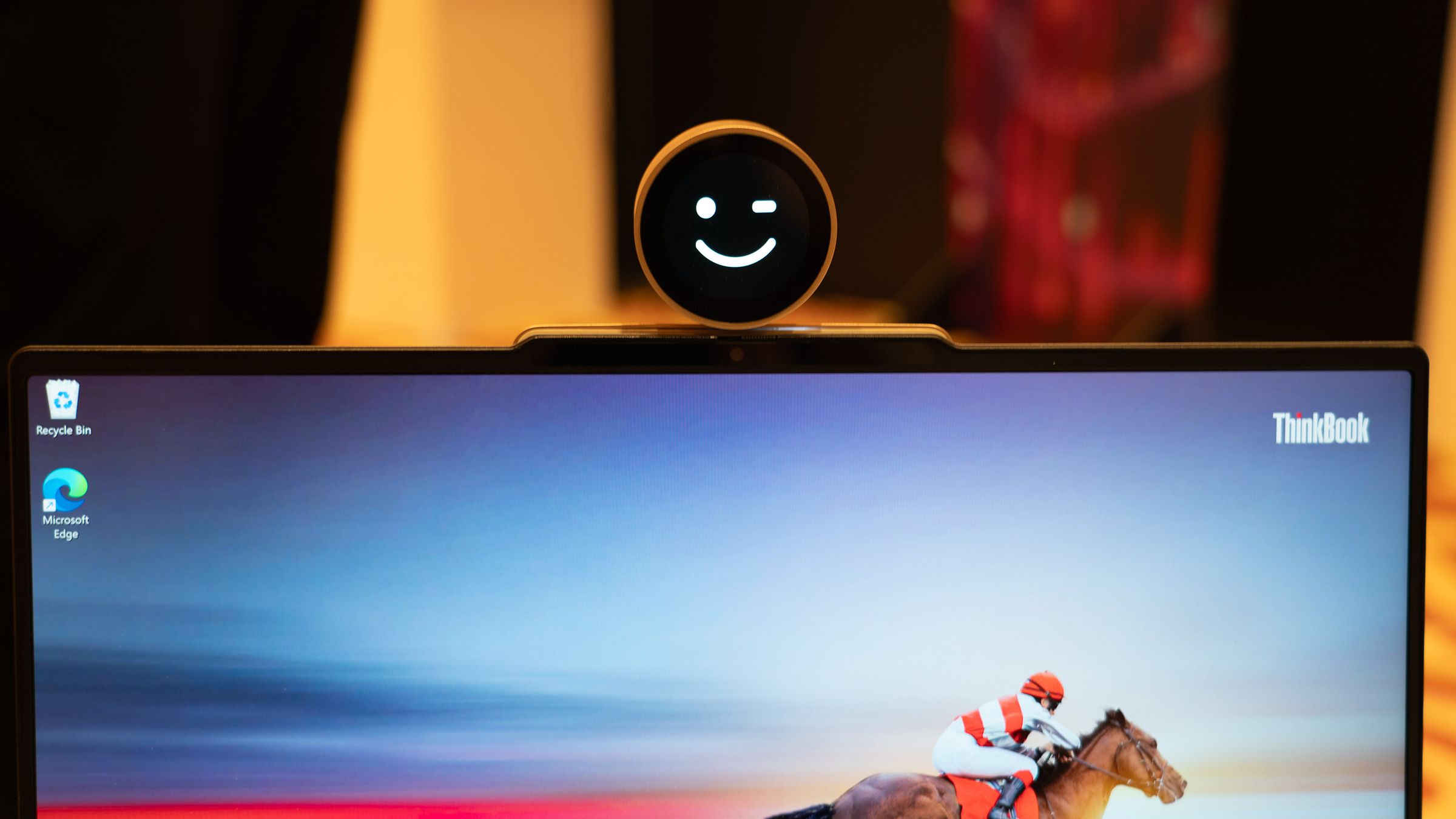 An image of black-and-white smiley face winking. The face appears to be set in a webcam attached to the top of a laptop.