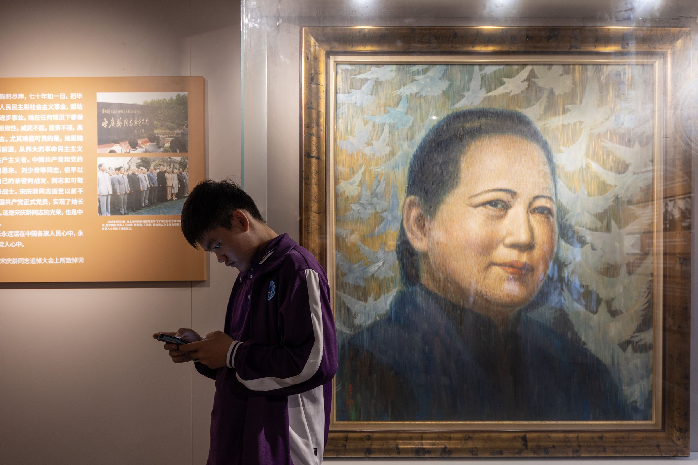 A boy looks at his smart phone by Song Qingling’s portrait painting at Song Qingling’s ancestral residence on May 12th, 2023