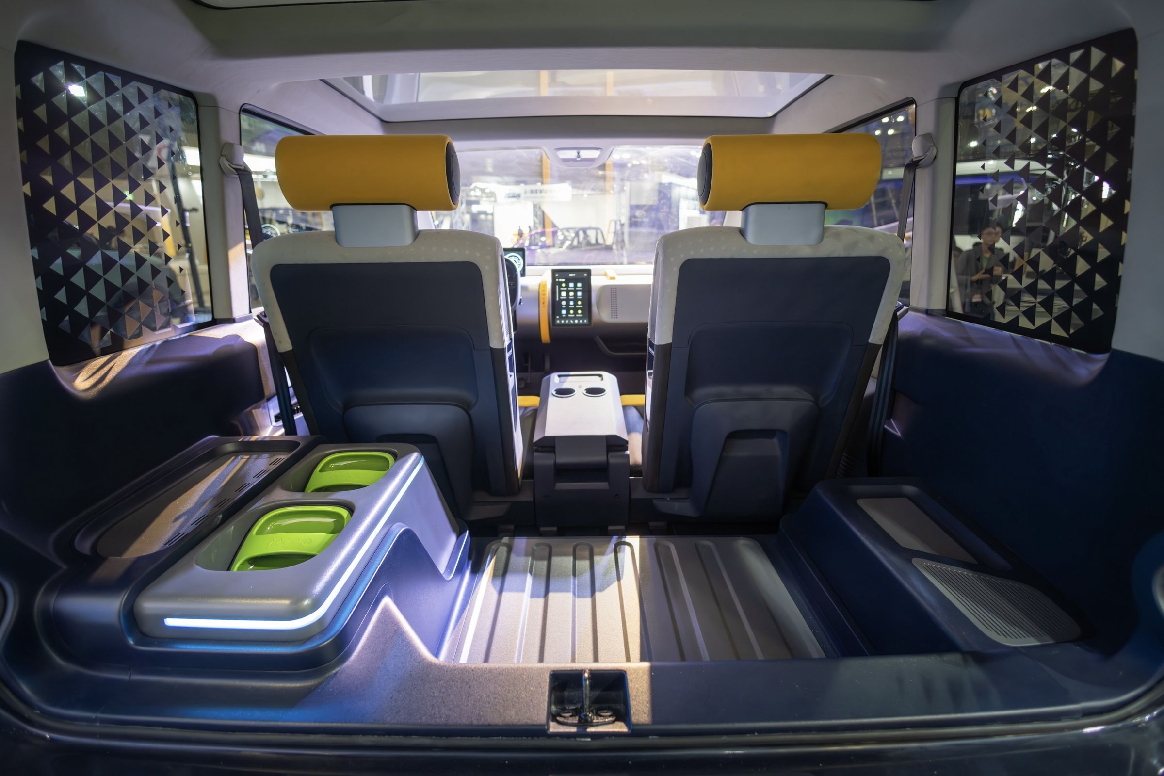 rear interior of small car with side bench for a third passenger and two green battery packs to the left.