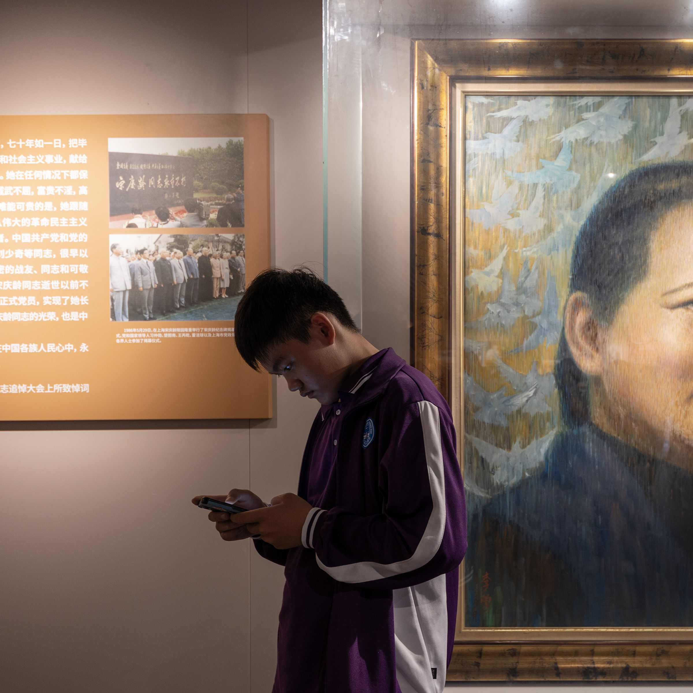 A boy looks at his smart phone by Song Qingling’s portrait painting at Song Qingling’s ancestral residence on May 12th, 2023