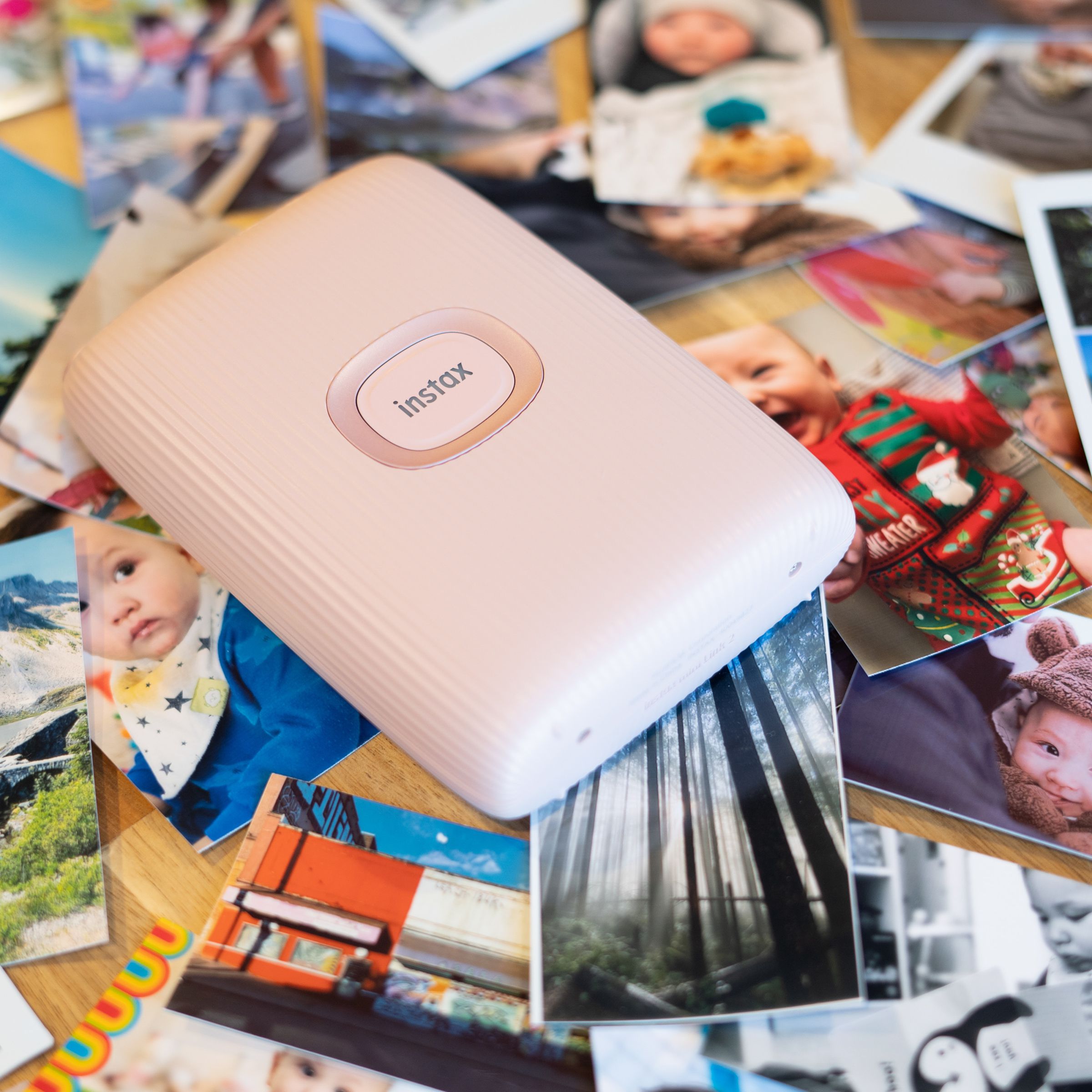 Instax Mini Link 2 on a backdrop of printed photos.