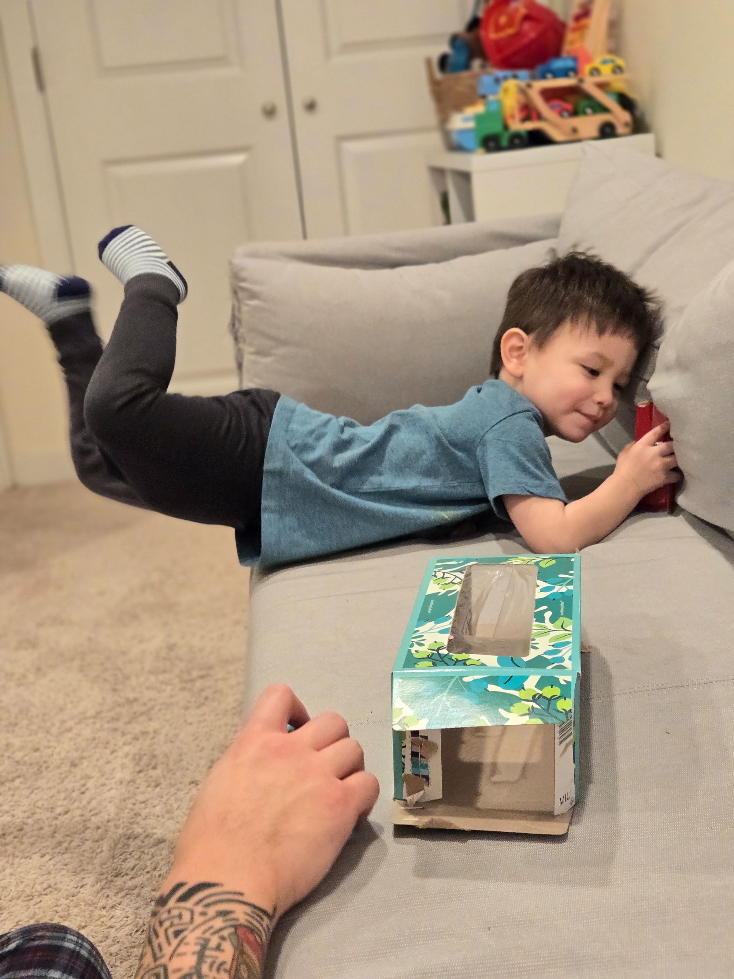 Photo of a child on a couch with blurred arm in the foreground.