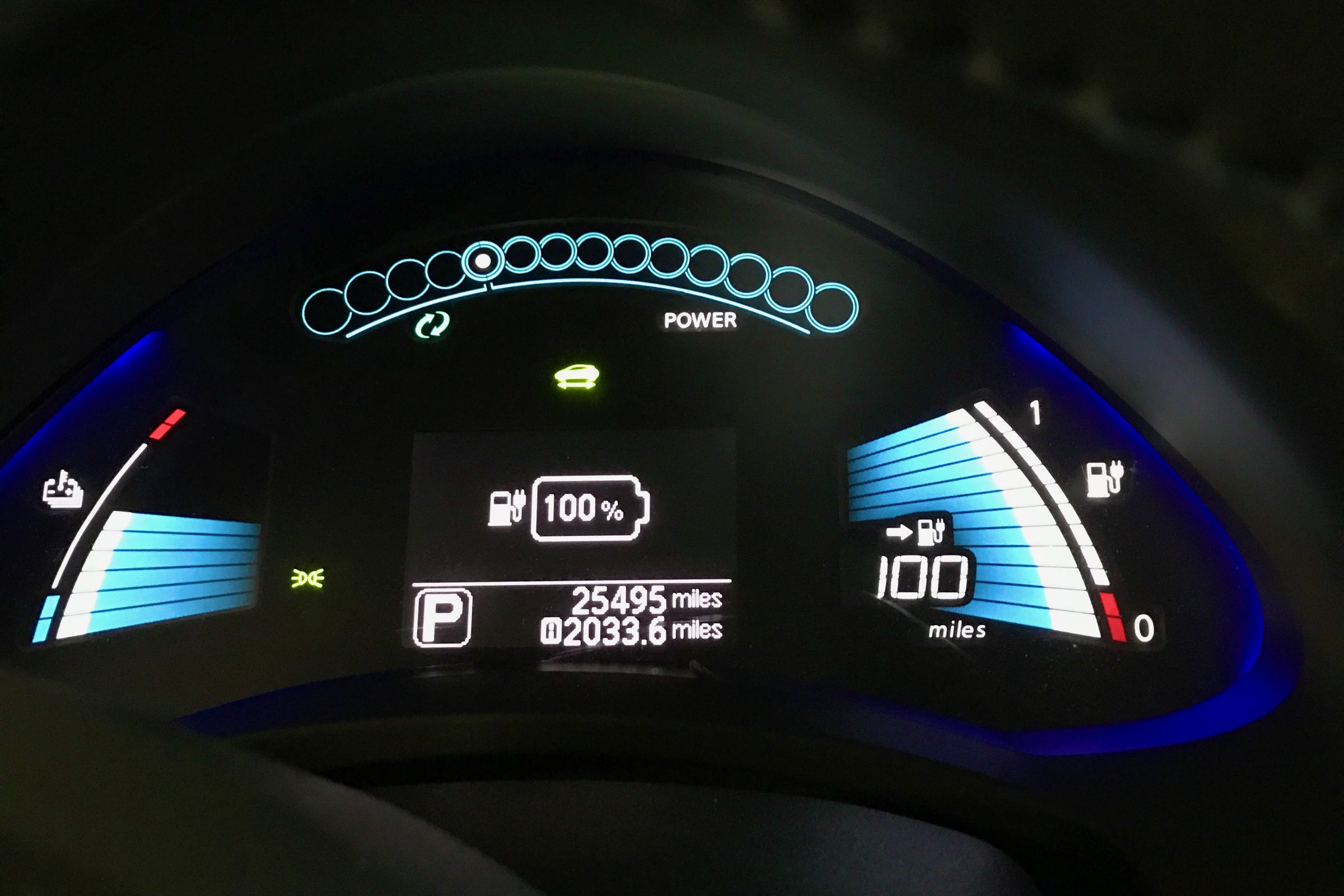 This is the dashboard of a 2015 Nissan Leaf that shows the medium battery temperature on the left side that looks like a blue fan with white tips, and a full battery meter on the right with the same style. The middle shows a battery icon that says 100 percent, and the battery meter on the left shows twelve bars and a 100 mile range.