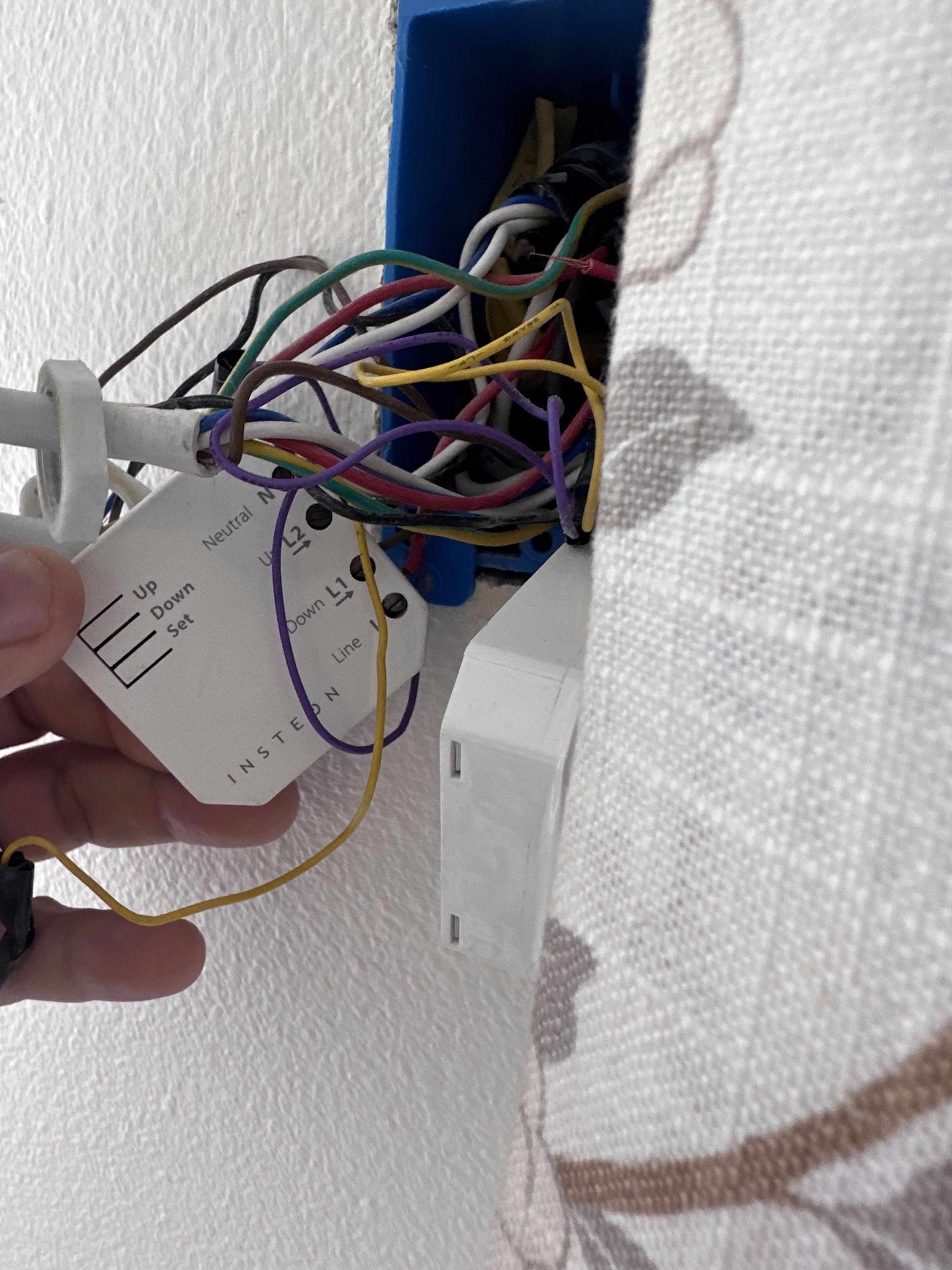 A close-up of a small white box with multiple colored wires coming out of it. The Insteon logo is very apparent.