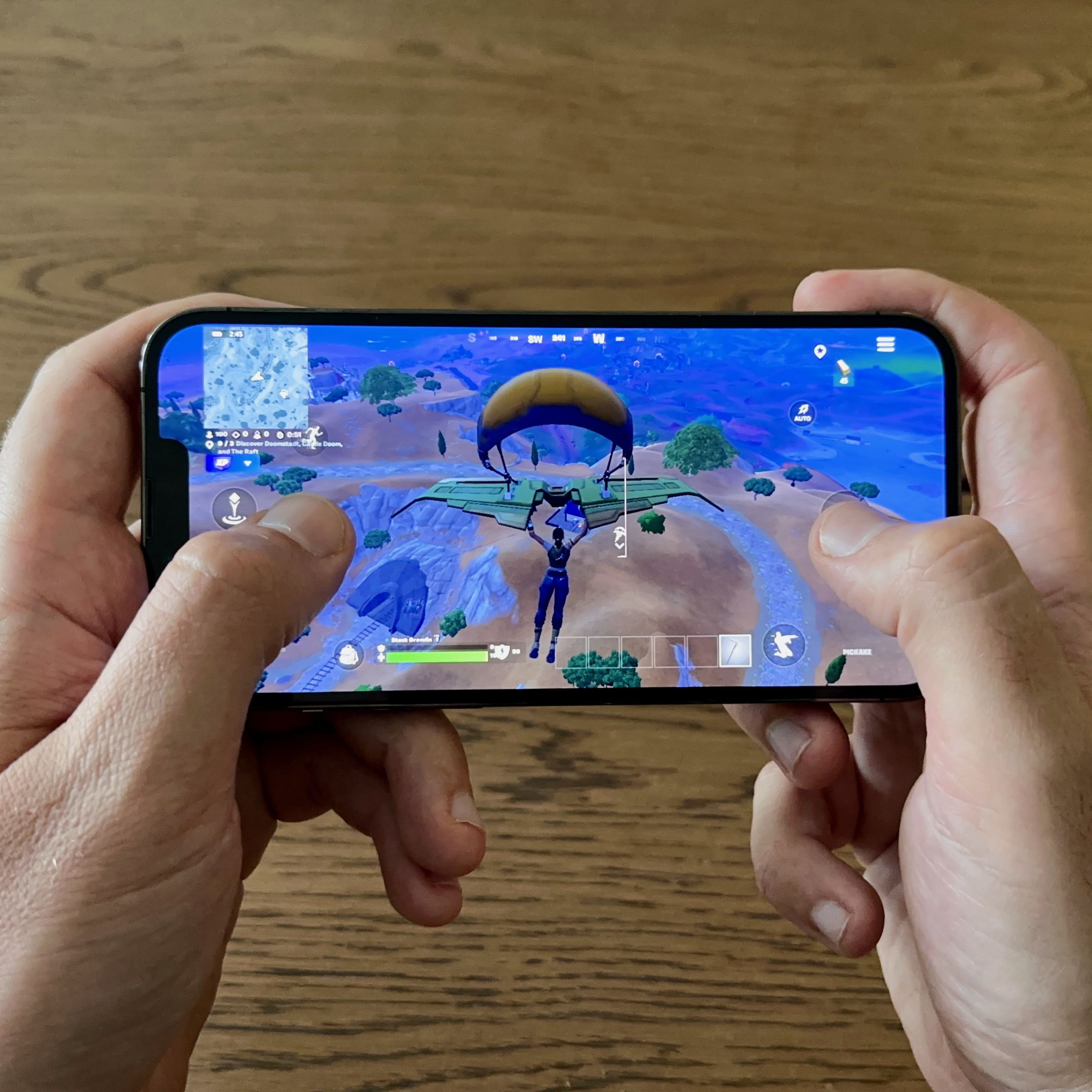 An iPhone being held with two hands playing Fortnite.