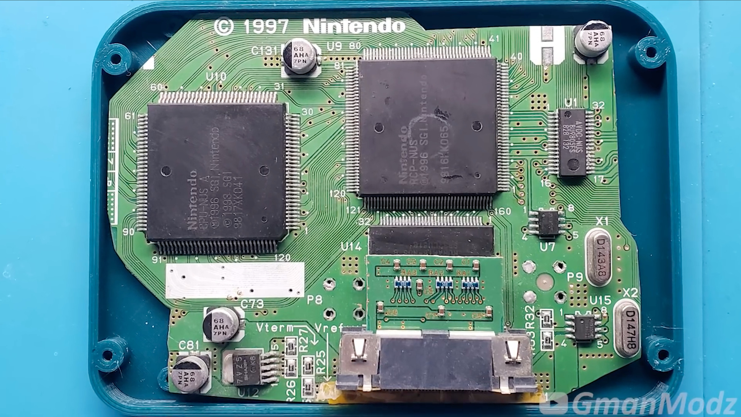 A picture of a Nintendo 64 motherboard sitting inside a small case.
