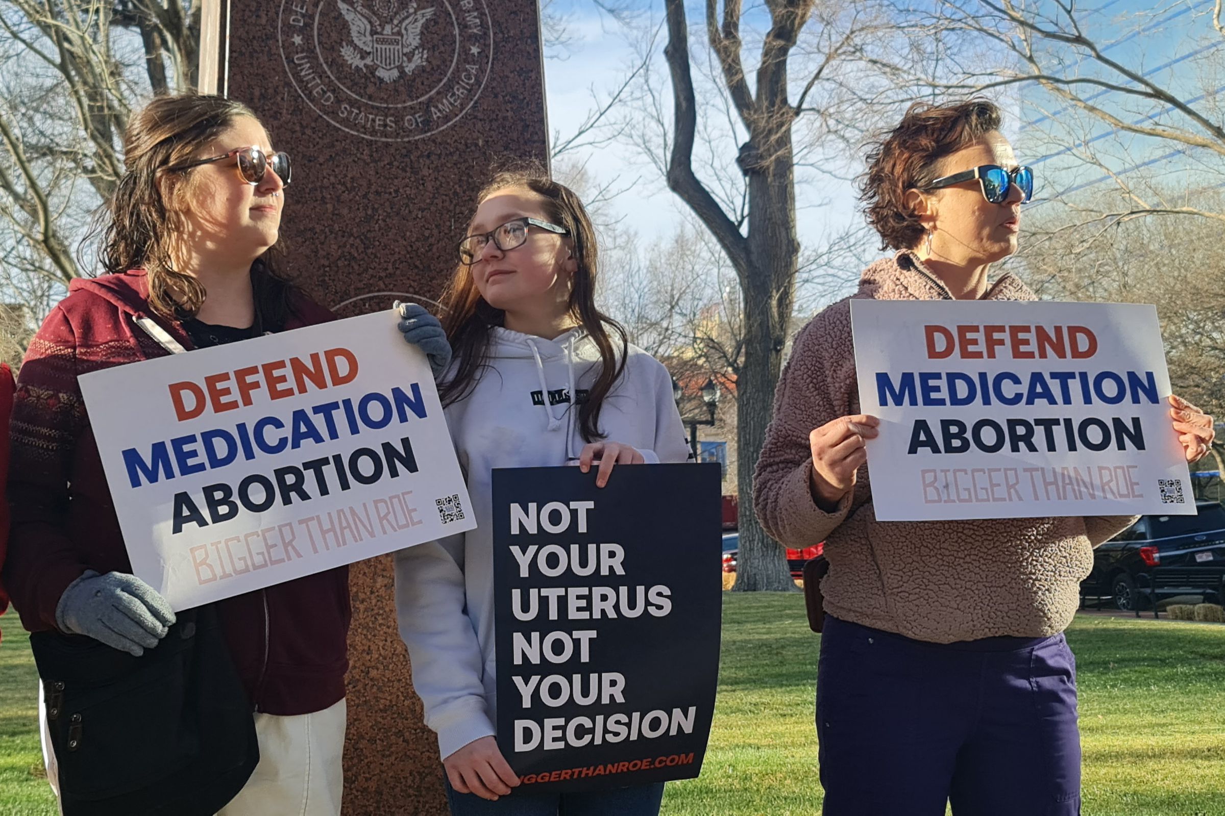 Protestors holding signs that read “defend medication abortion” and “not your uterus not your decision.”