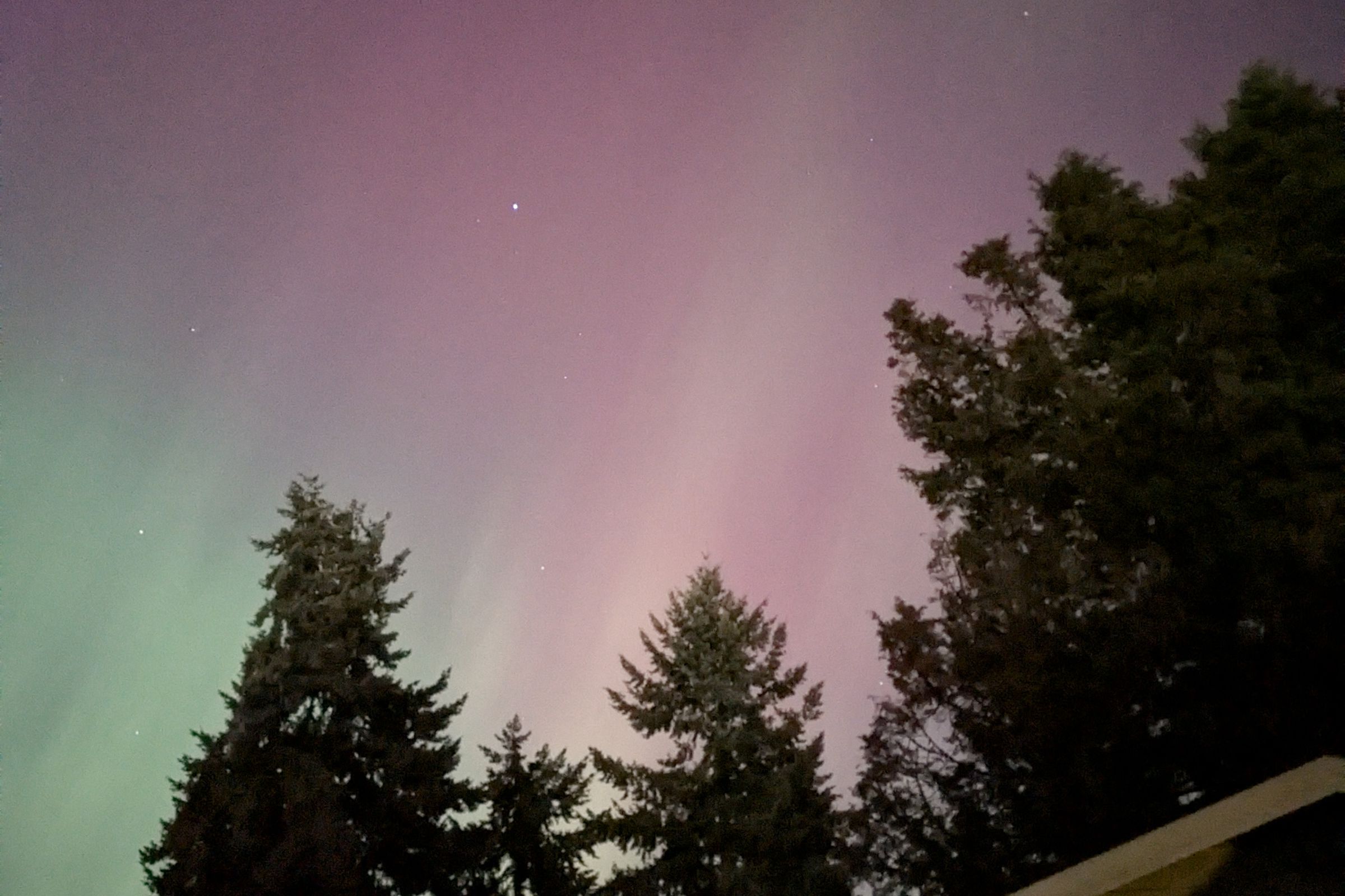 Photo of northern lights over a rooftop.