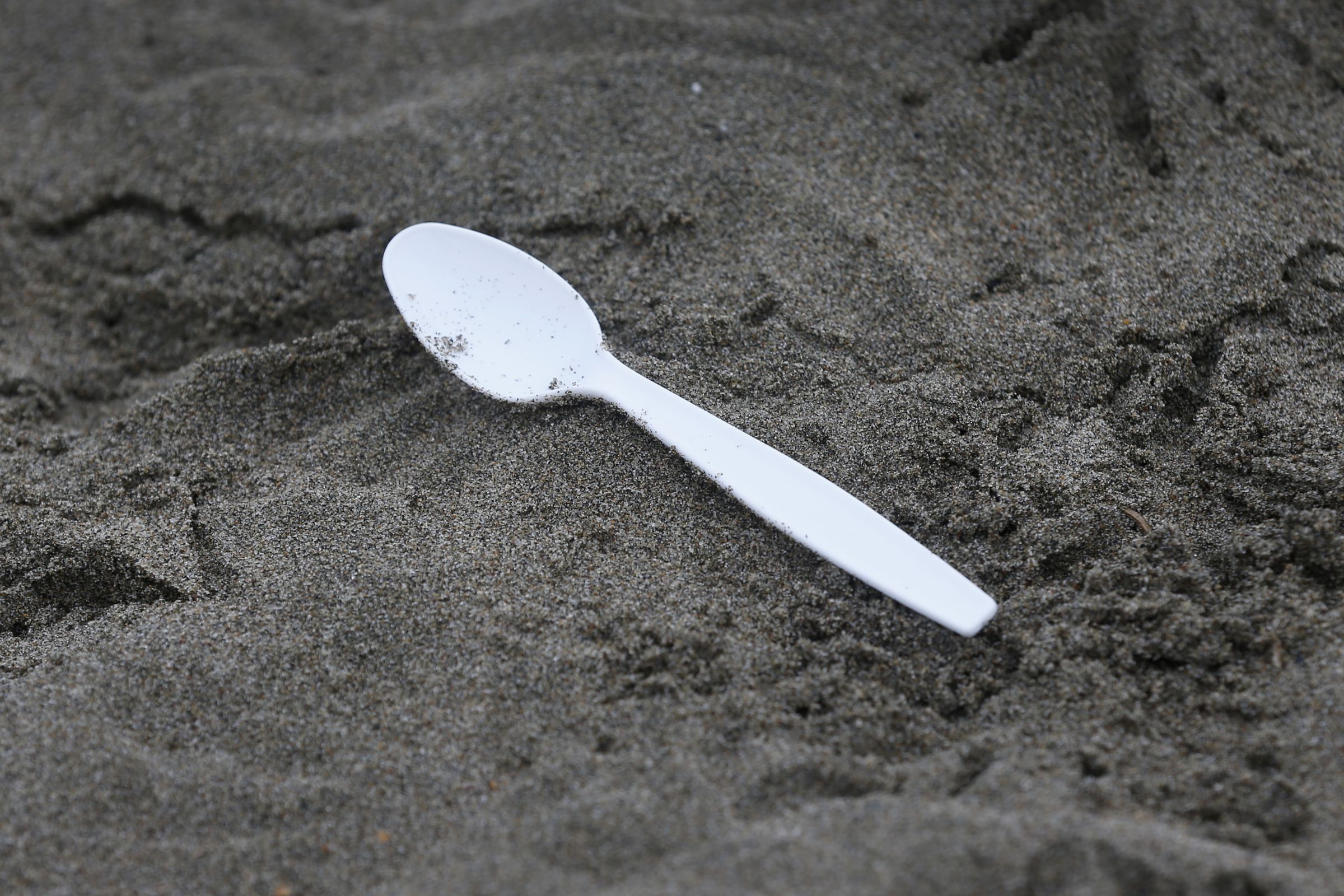 An image showing a plastic spoon littered on the beach