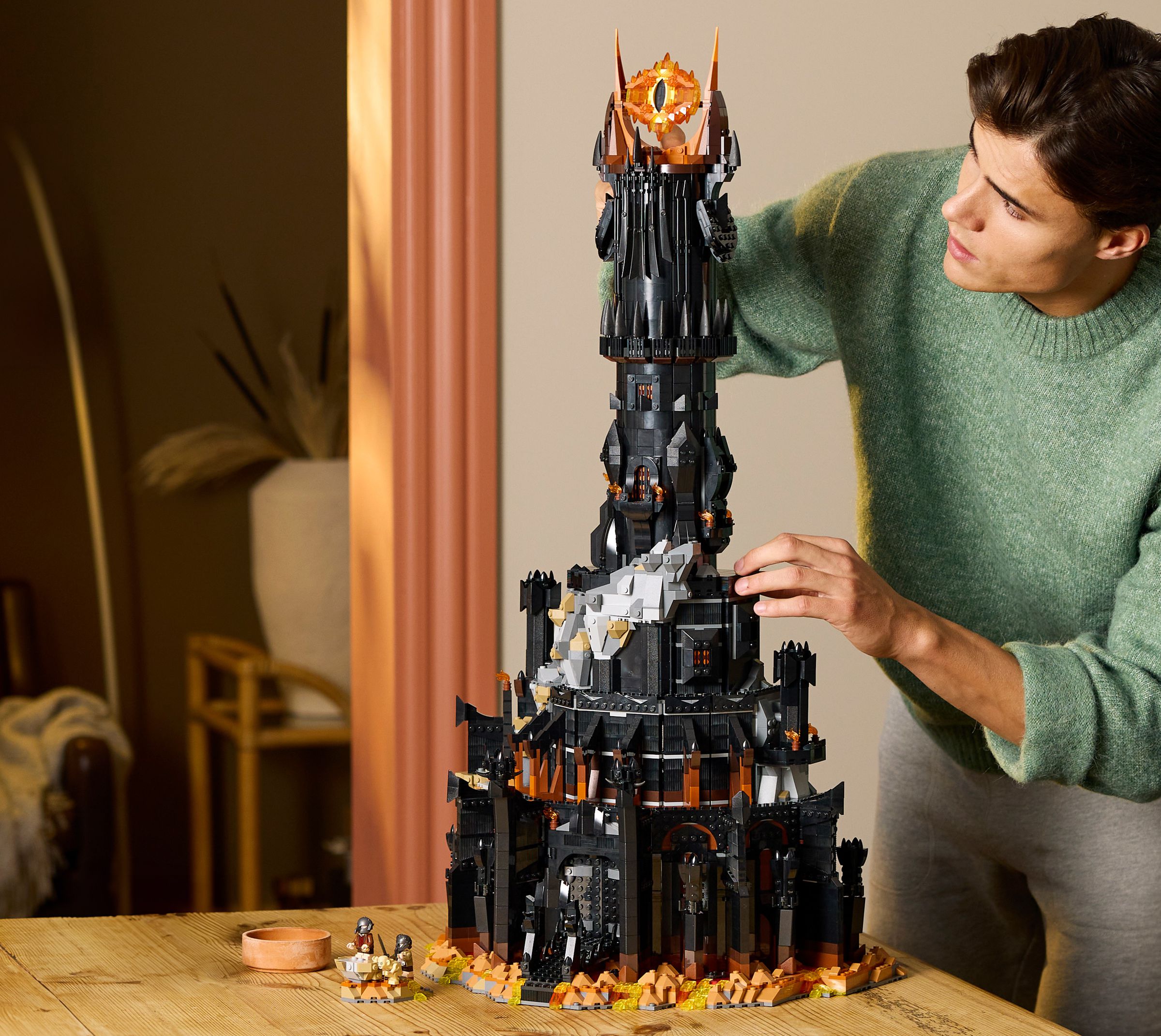 A person stands next to a black tower made of Lego bricks with a giant flaming eye on top