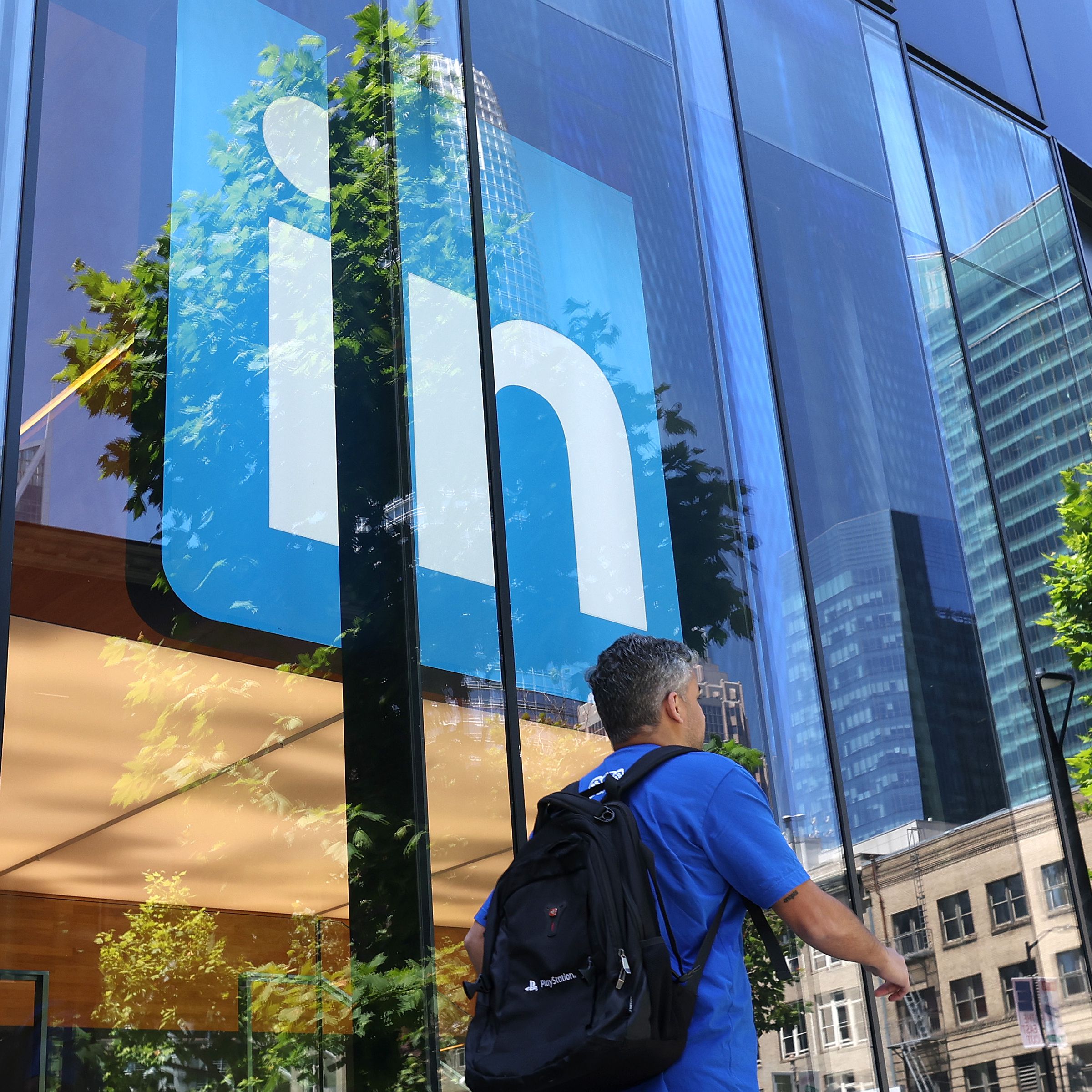 A pedestrian walks by a sign at a LinkedIn office on July 26, 2023 in San Francisco, California. LinkedIn announced plans to cut nearly 200 jobs at offices in the San Francisco Bay Area. The cuts follow 700 layoffs earlier in the year.