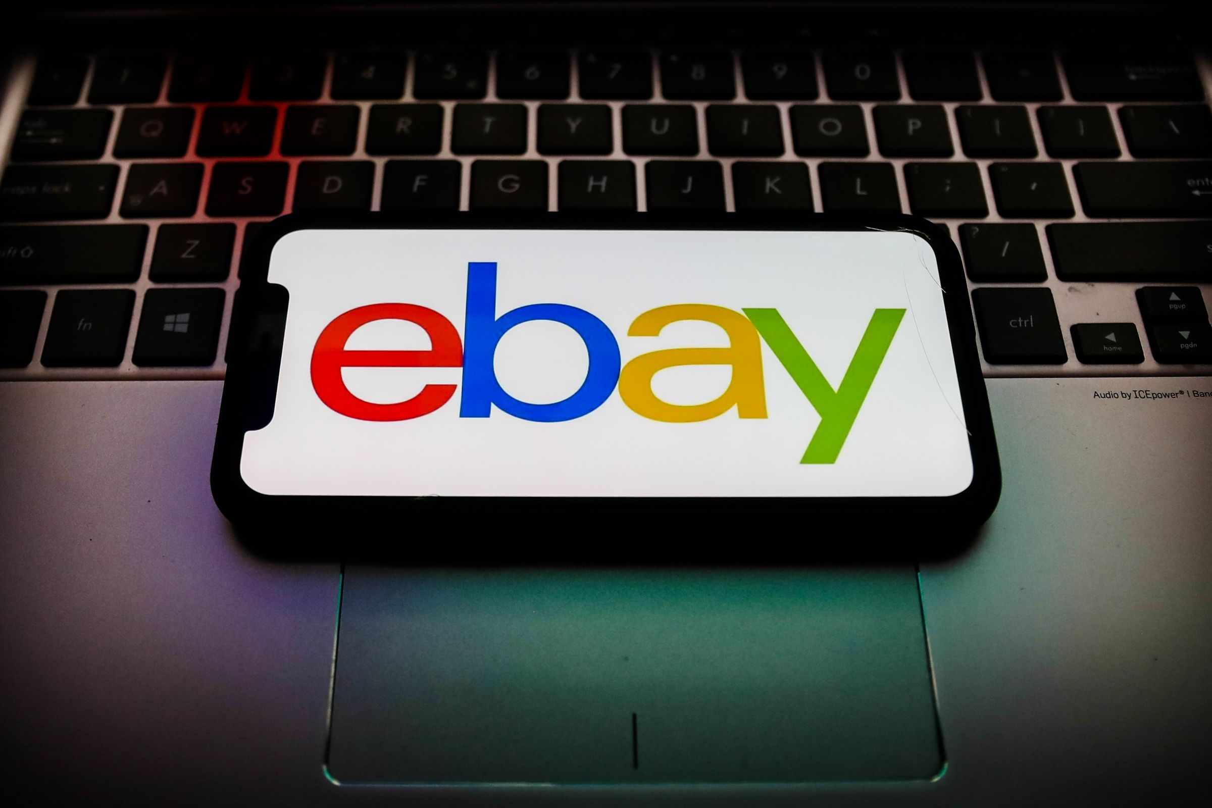 Photo of a phone showing the eBay logo, set on top of a laptop keyboard.