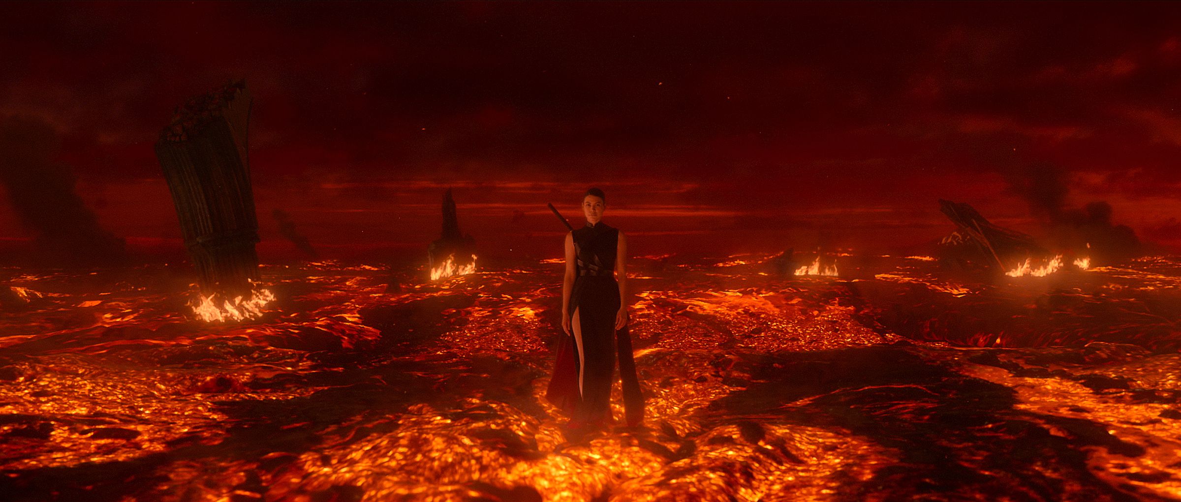 A woman in form fitting dress walking across a fiery landscape where the ground seems to be lava.