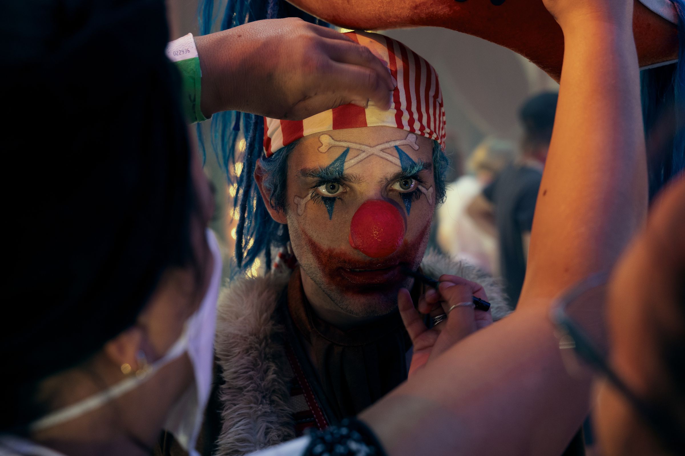 A close-up shop of an actor made up to look like a clown as production workers fine-tune his makeup in between shoots.