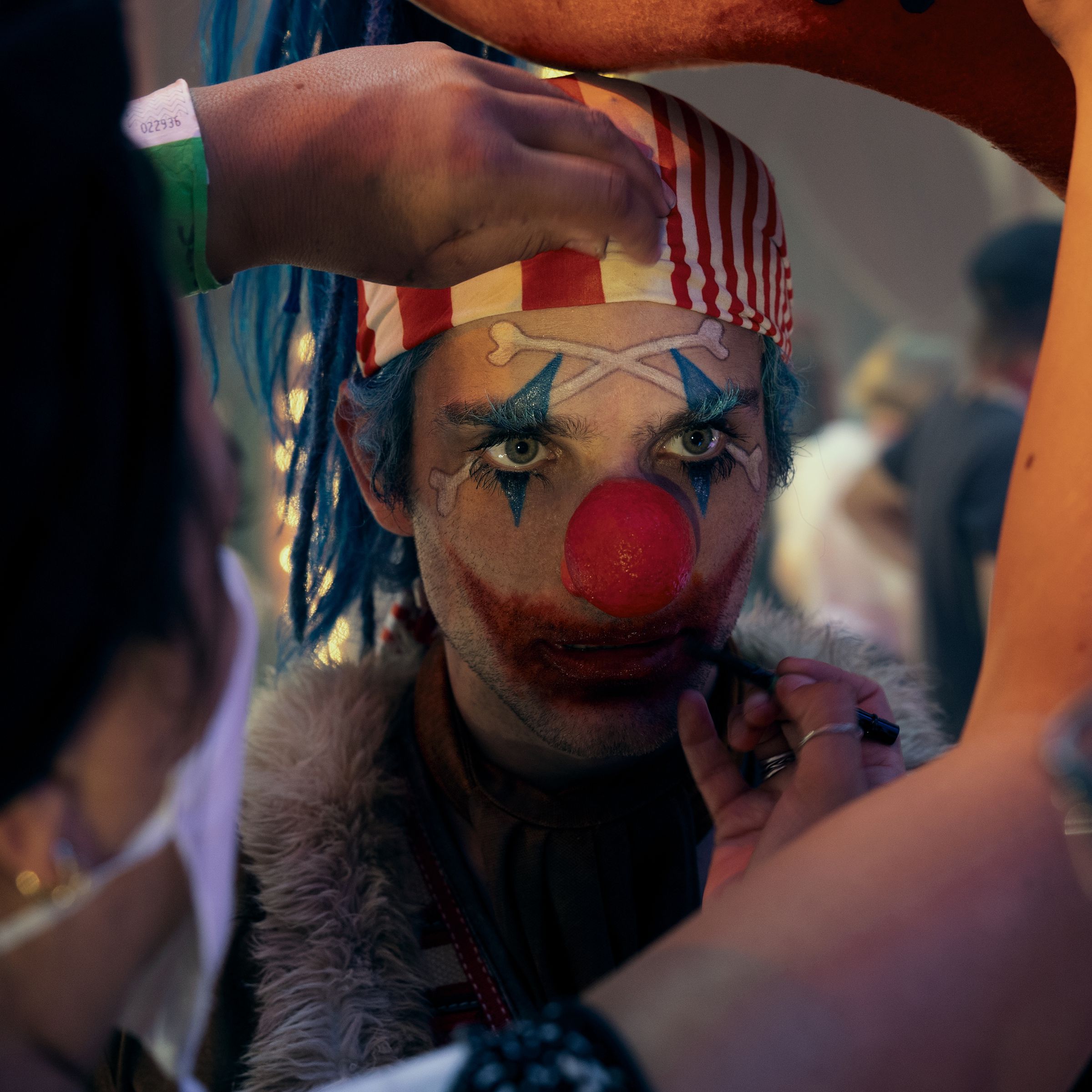 A close-up shop of an actor made up to look like a clown as production workers fine-tune his makeup in between shoots.