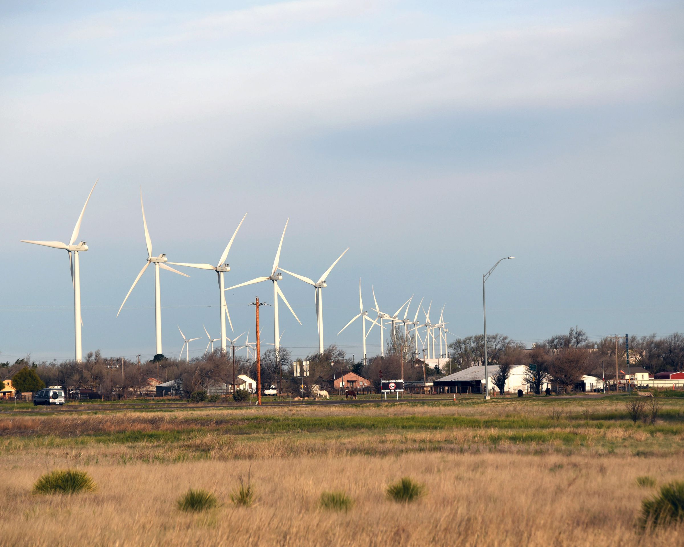 Wind turbines stand behind homes
