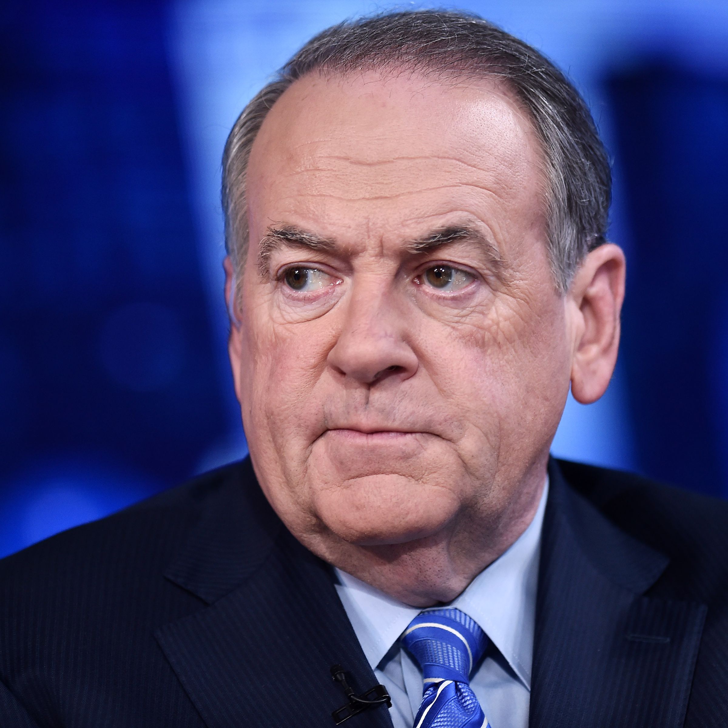 Mike Huckabee photographed from the shoulders up. He is wearing a suit and has a tense look on his face.