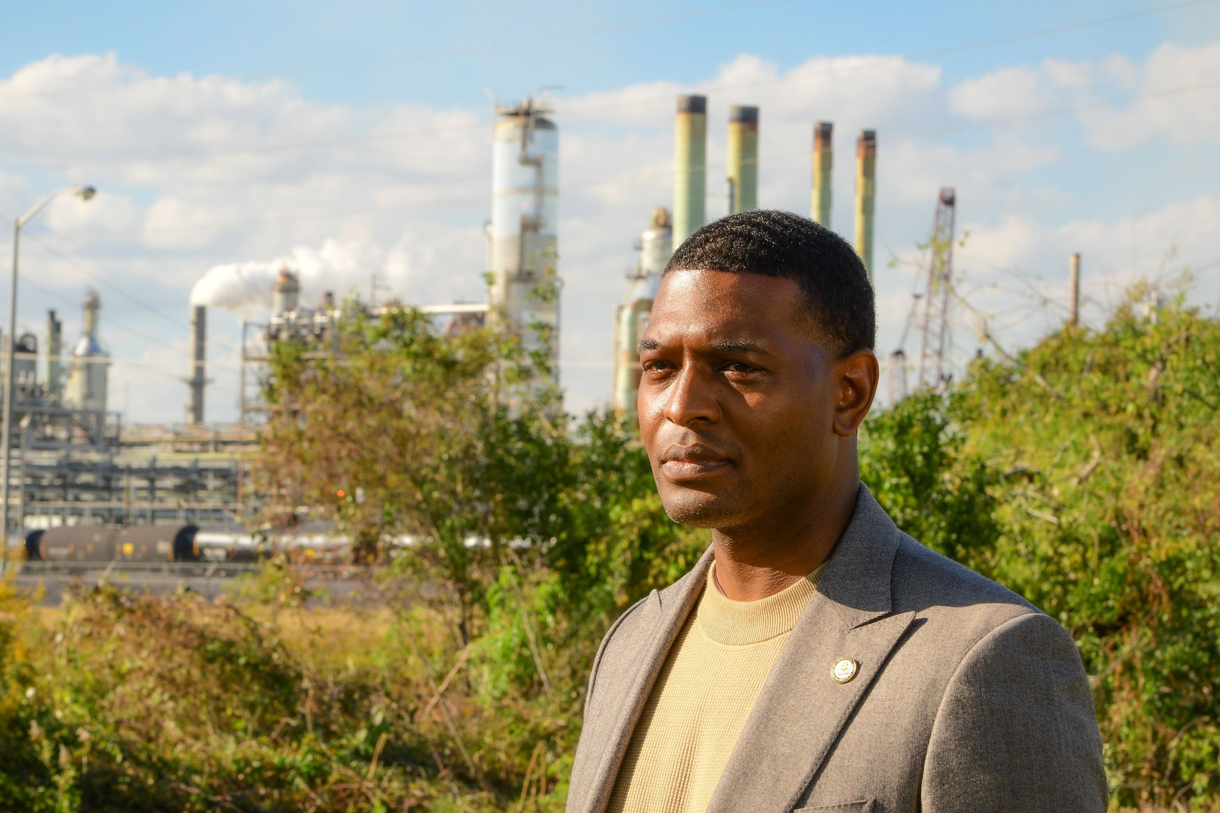 A close-up photo of Michael Regan with an industrial facility that looks like a power plant behind him.