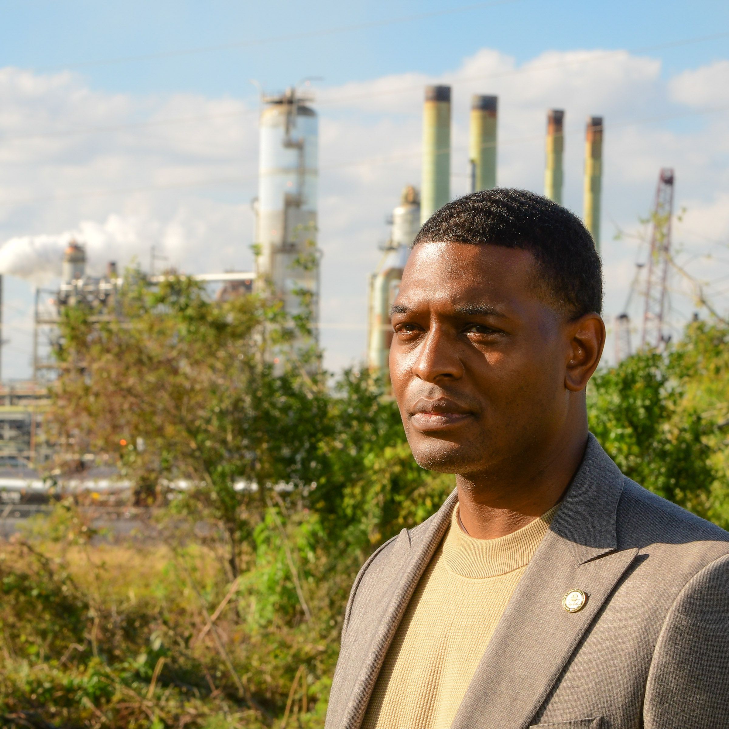 A close-up photo of Michael Regan with an industrial facility that looks like a power plant behind him.