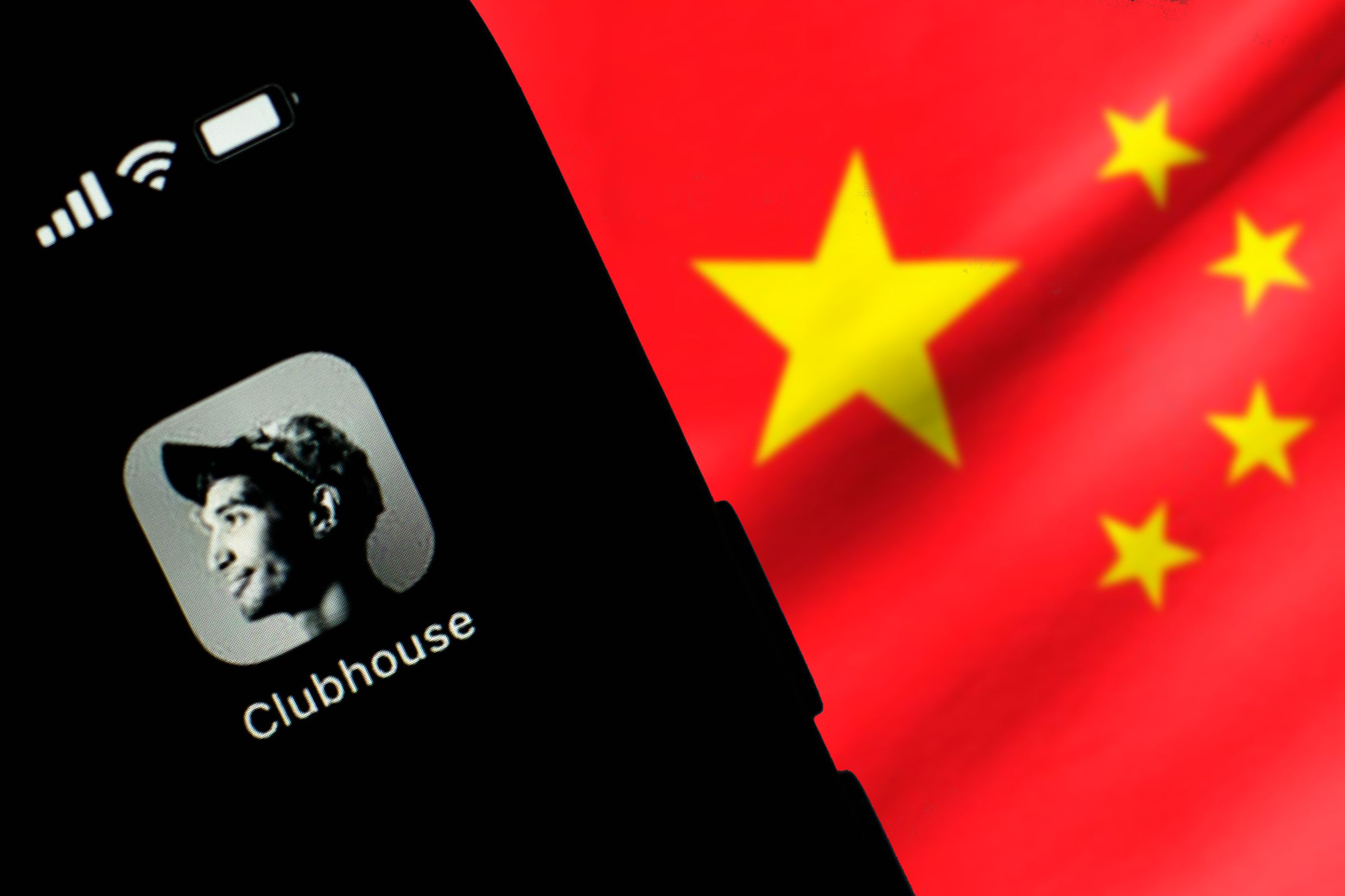In this photo illustration, the Clubhouse logo seen displayed on a smartphone screen in front of the Chinese national flag