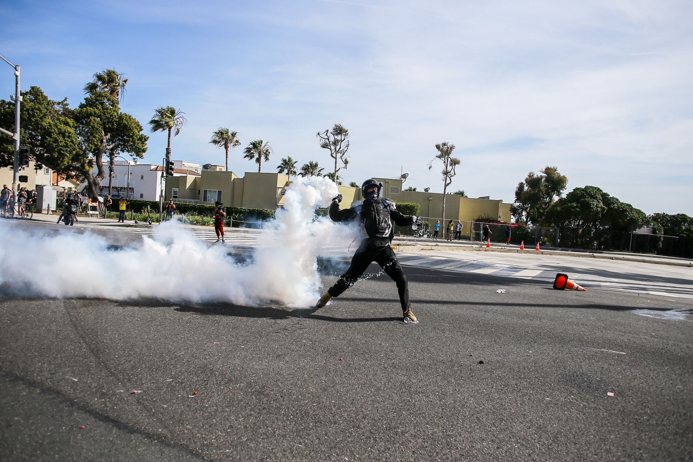 A protester return throws tear gas towards the police who...