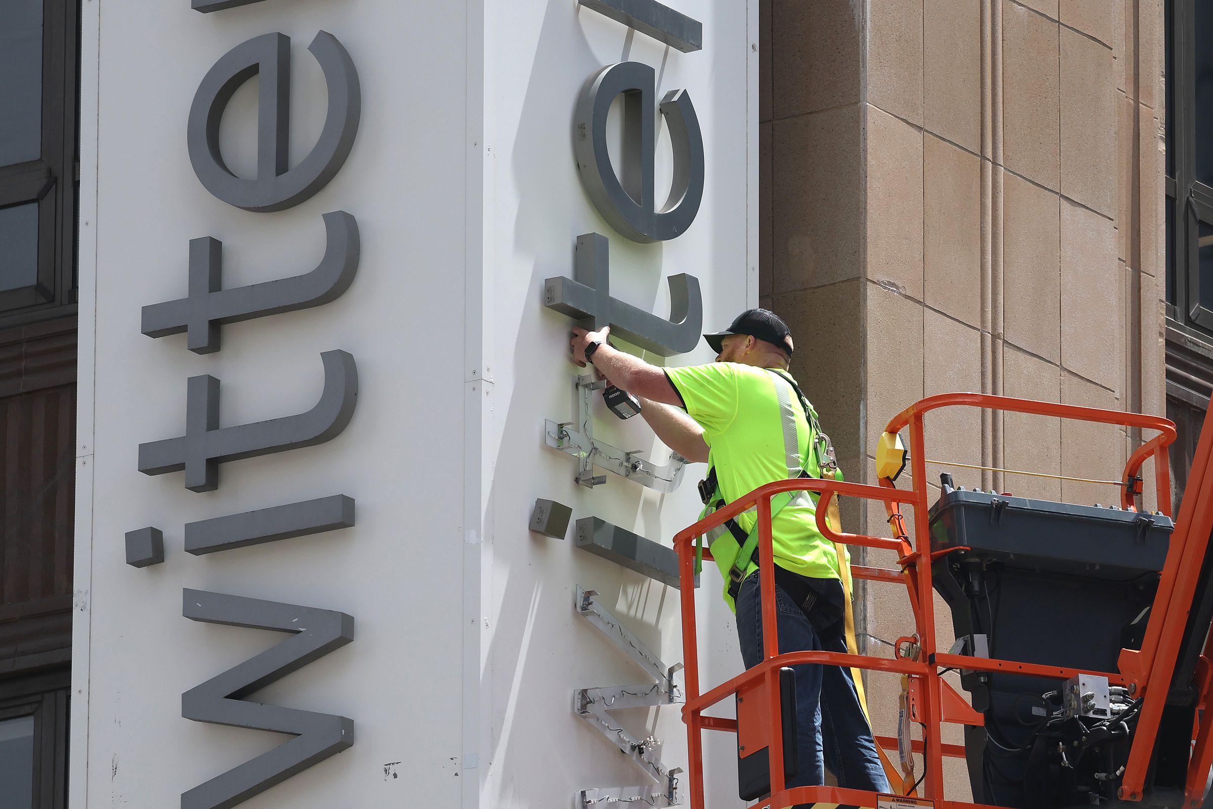 A worker removes letters from the Twitter sign that is posted on the exterior of Twitter headquarters.