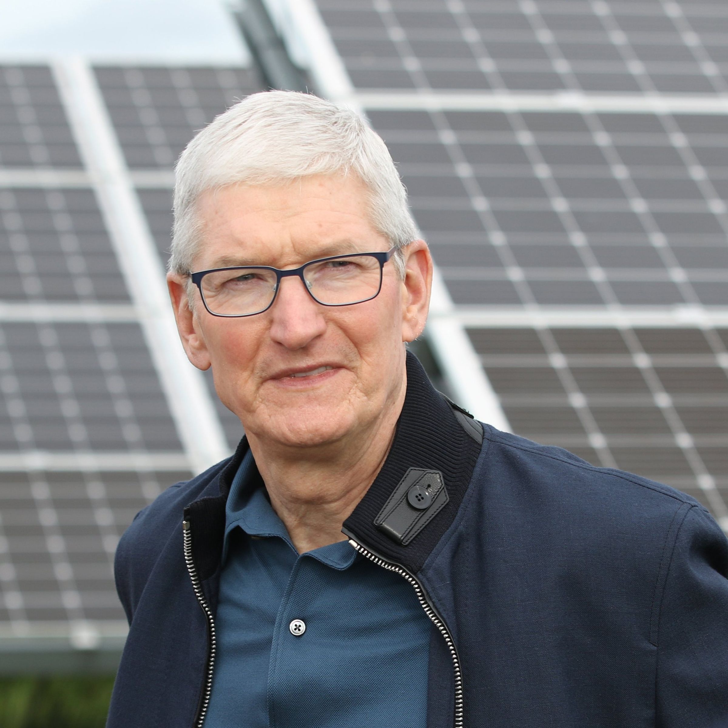 Tim Cook stand in front of large solar panels.