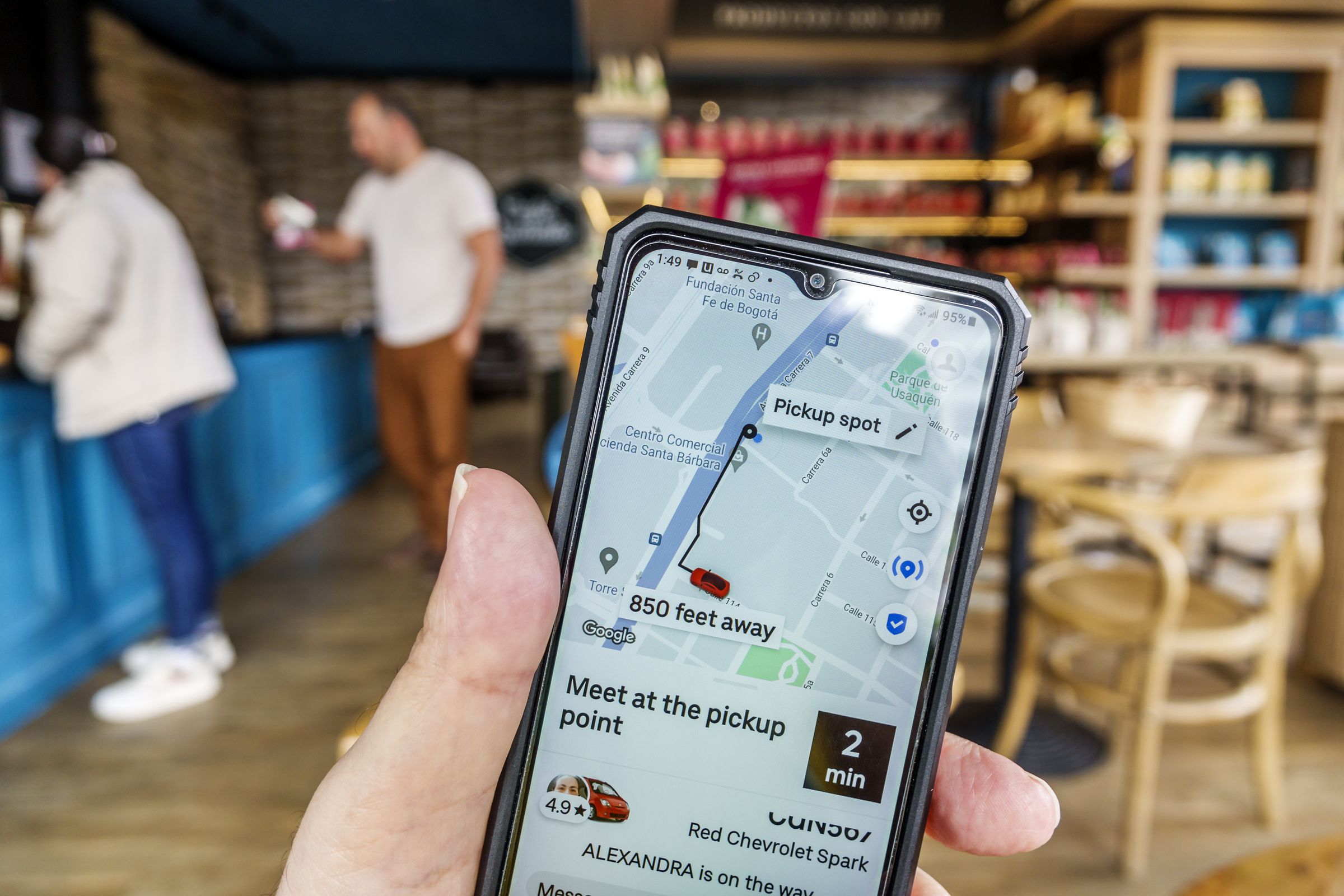 Bogota, Colombia, Usaquen, Cafe Quindio coffeeshop, tourist checks smartphone app for Uber driver location and arrival time