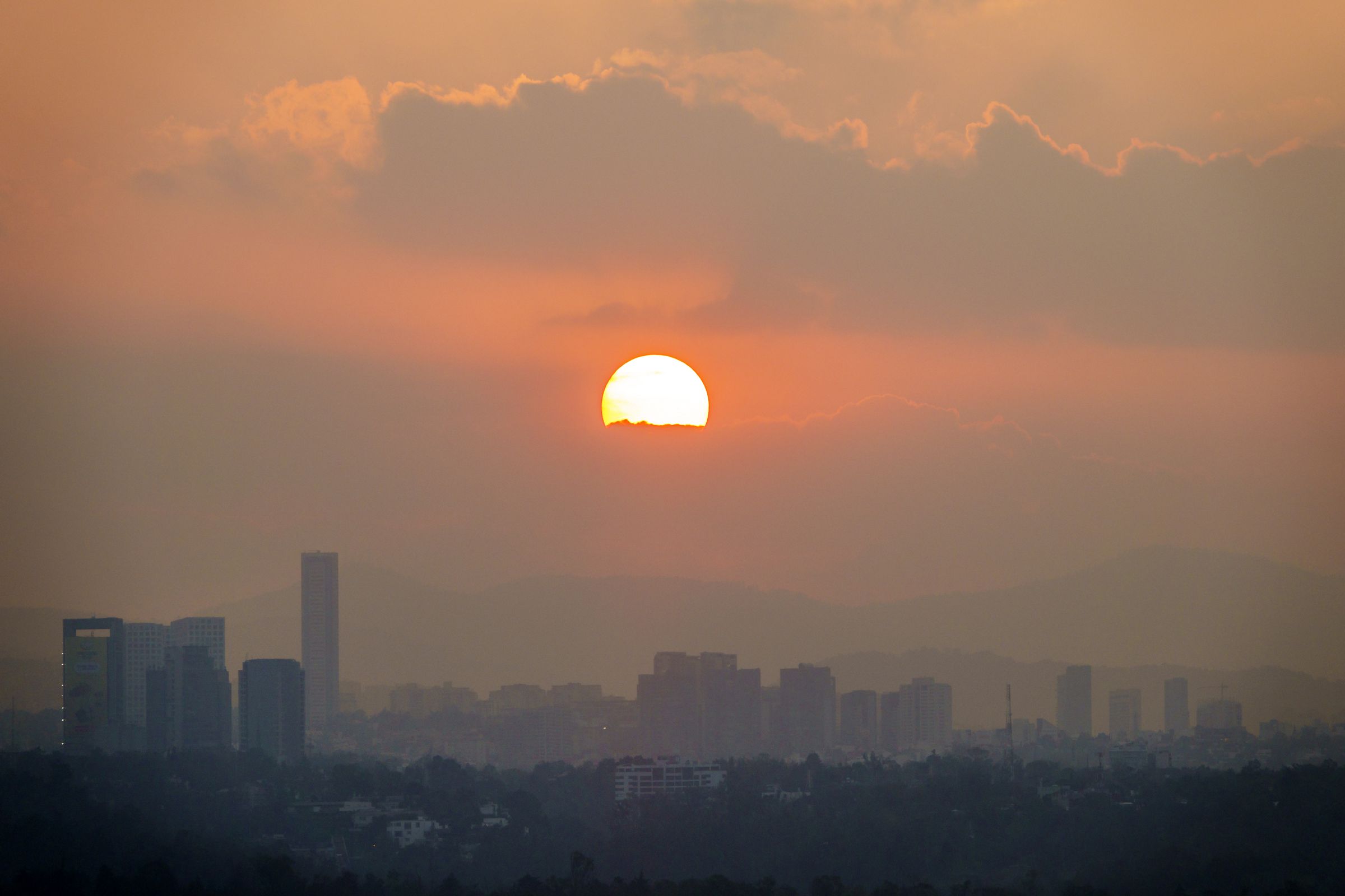 The city skyline at sunset, hazy with pollution.