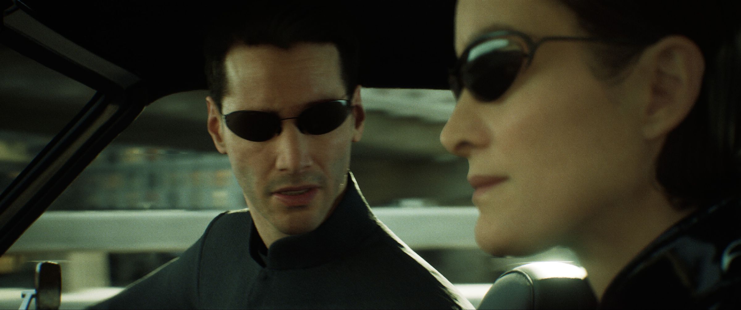 Image of a virtual Neo and Trinity from the Matrix, driving in a car wearing sunglasses.