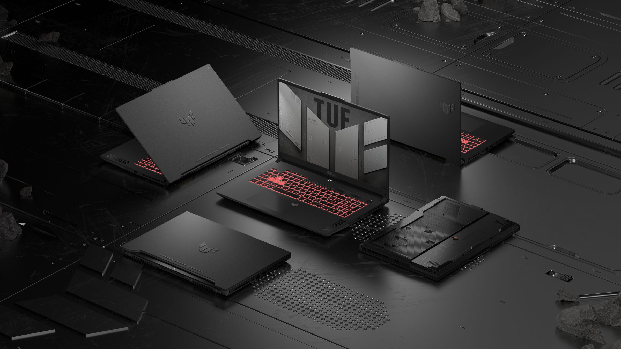 Five Asus TUF laptops arranged in a grid on a black table.