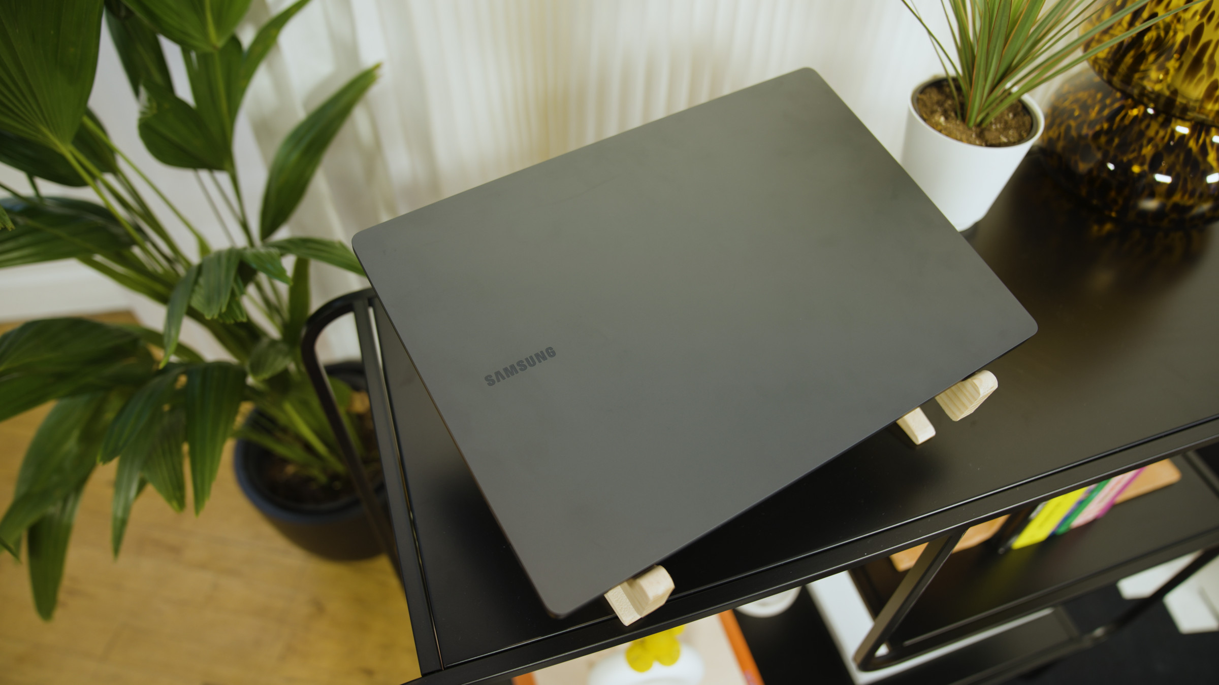 The Samsung Galaxy Book 3 Ultra lid seen from above with houseplants on either side.