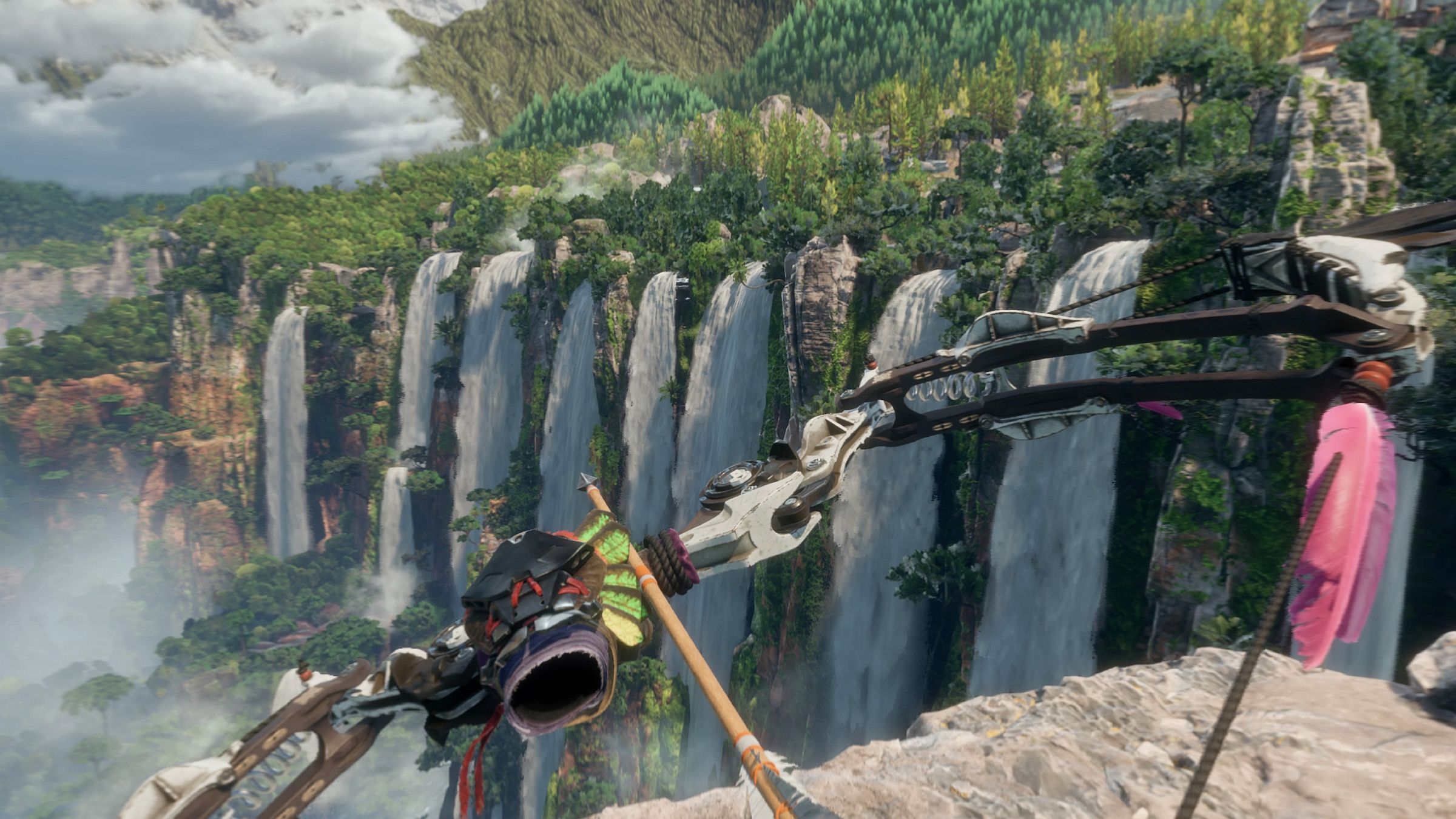 An ornate bow aloft, arrow nocked, standing atop a cliff overlooking an impressive array of nine waterfalls on the opposite cliff.